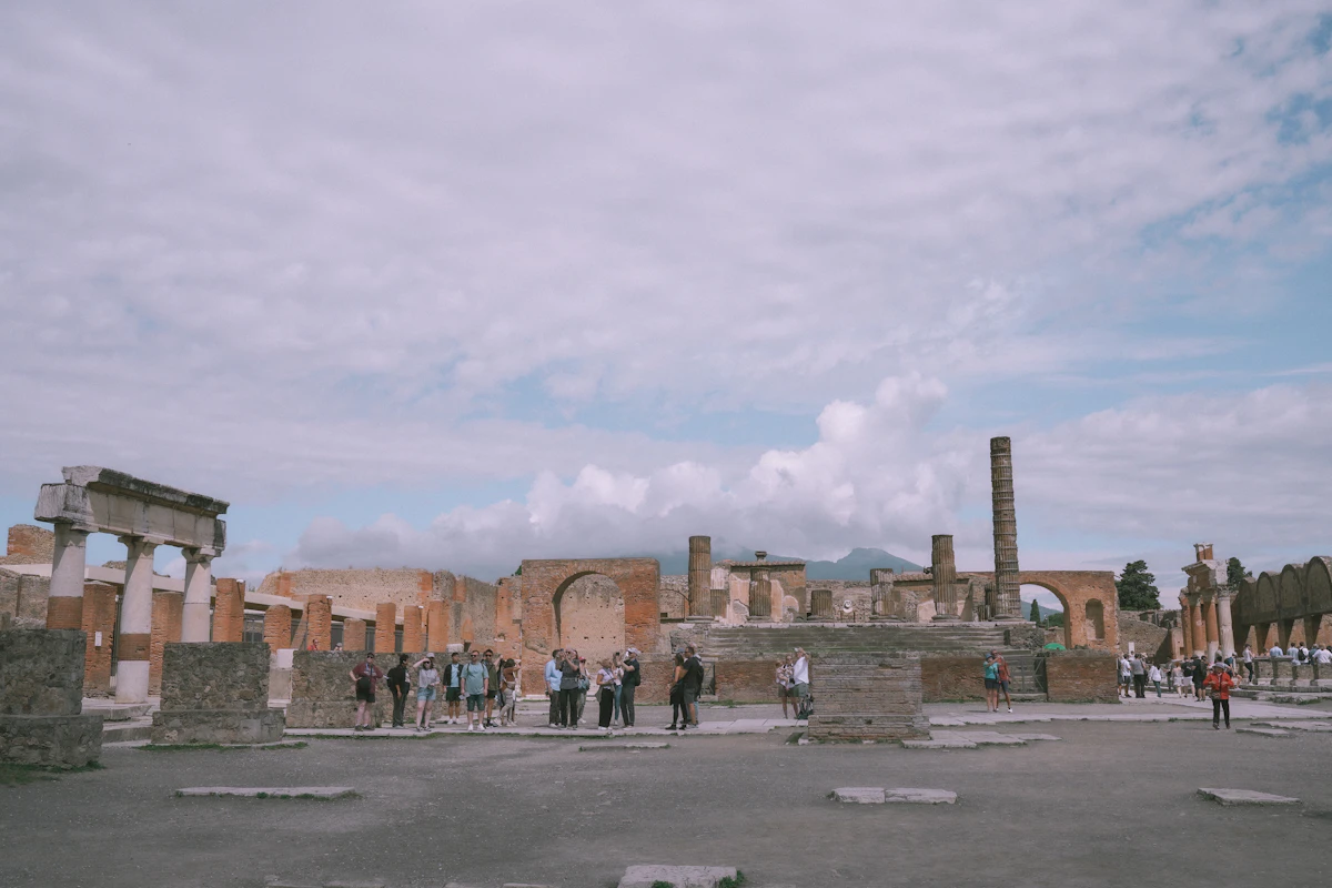 Ancient roman ruins with scattered tourists under cloudy sky
