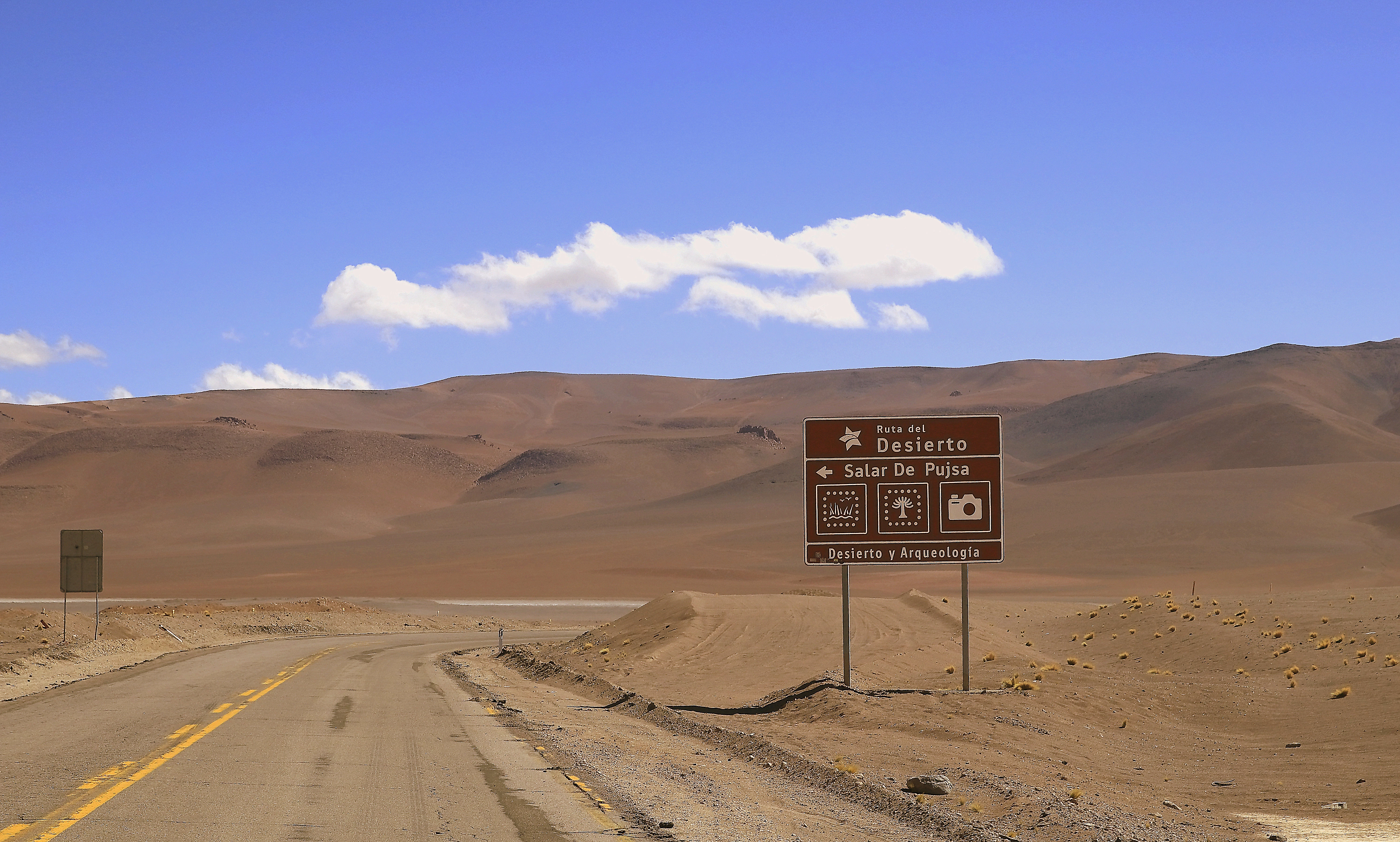 Road sign in a dry, mountainous landscape.