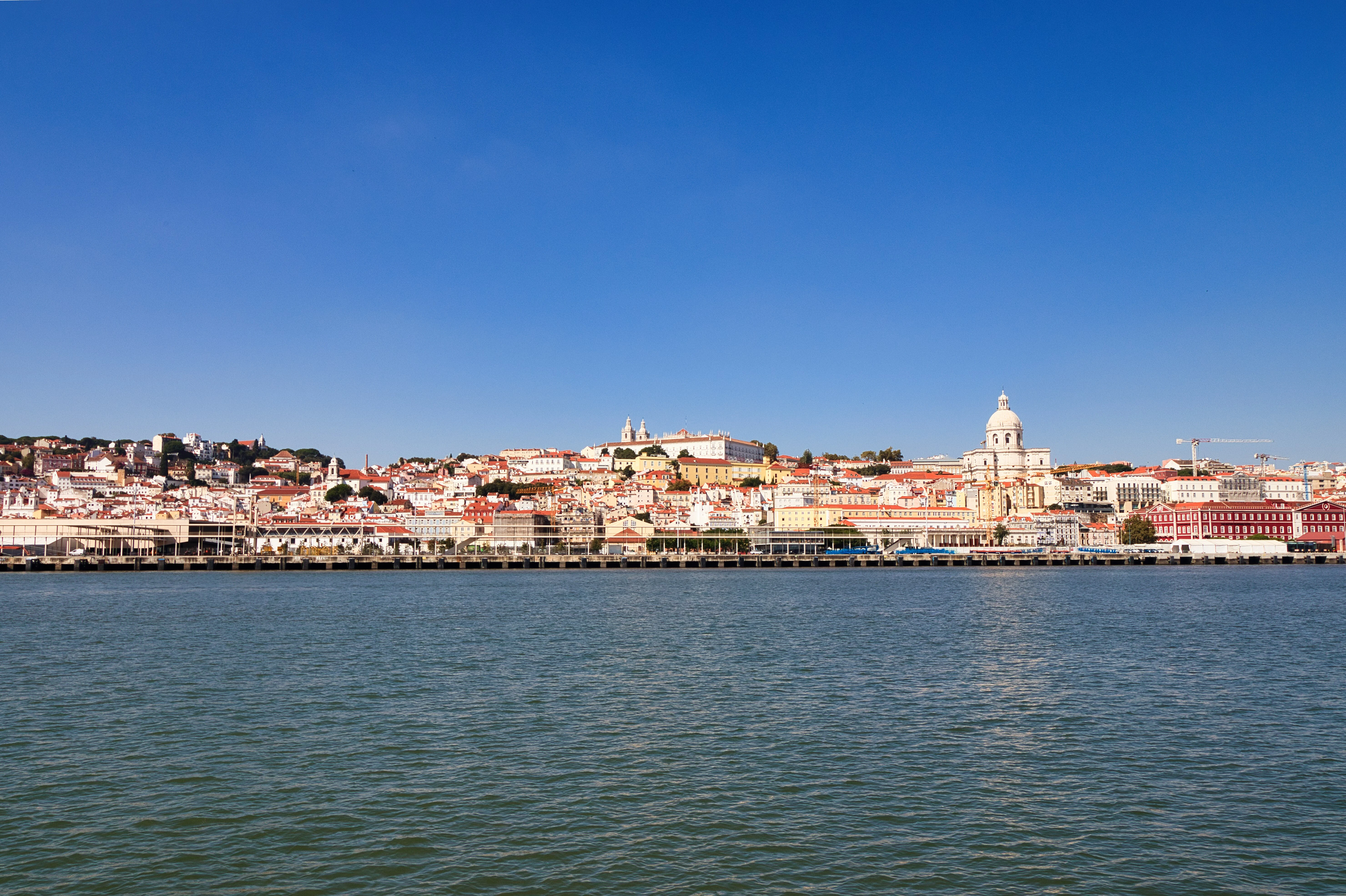 Cityscape overlooking a wide river under a clear blue sky.