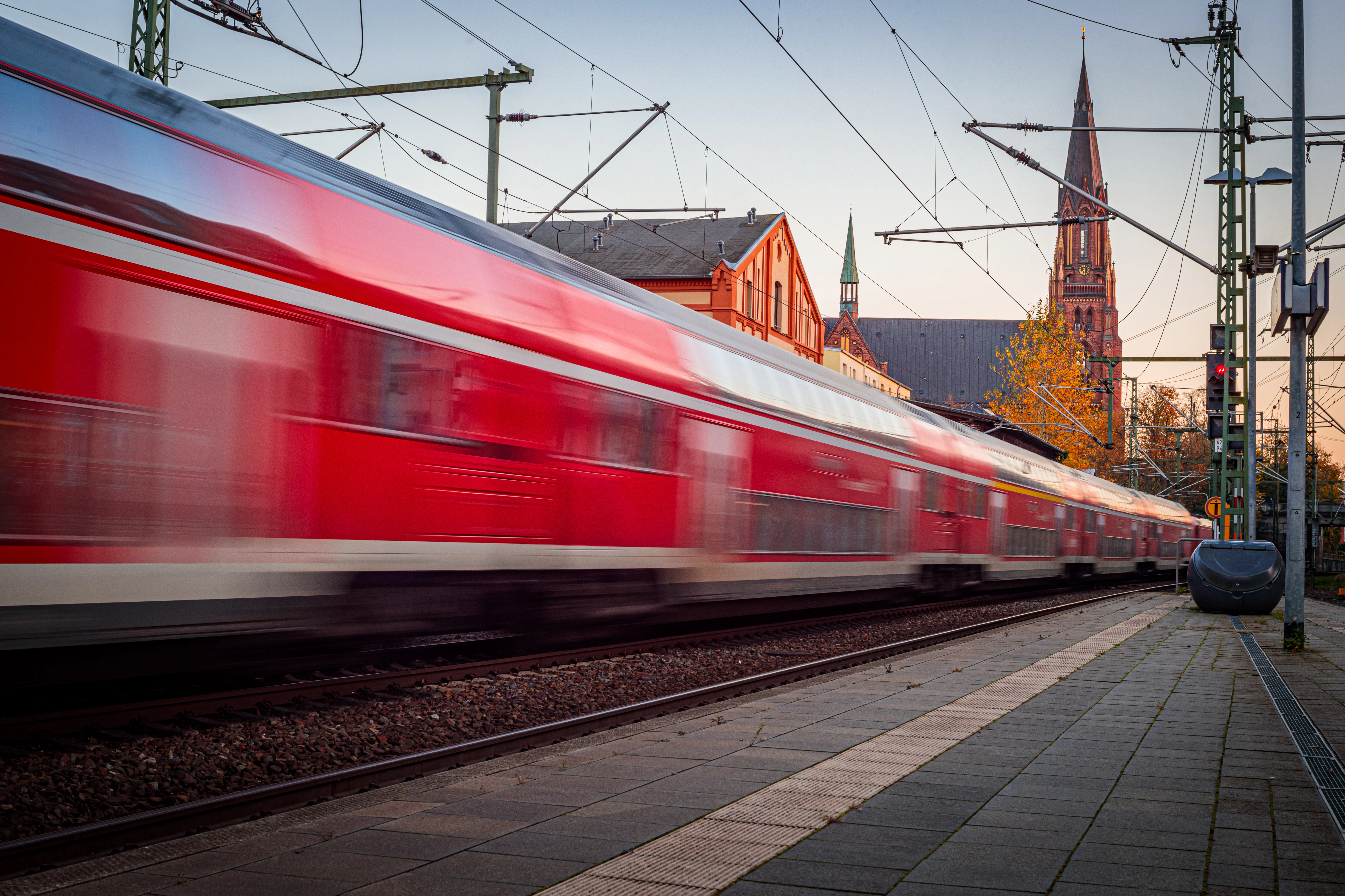 A red train traveling down train tracks next to a train station