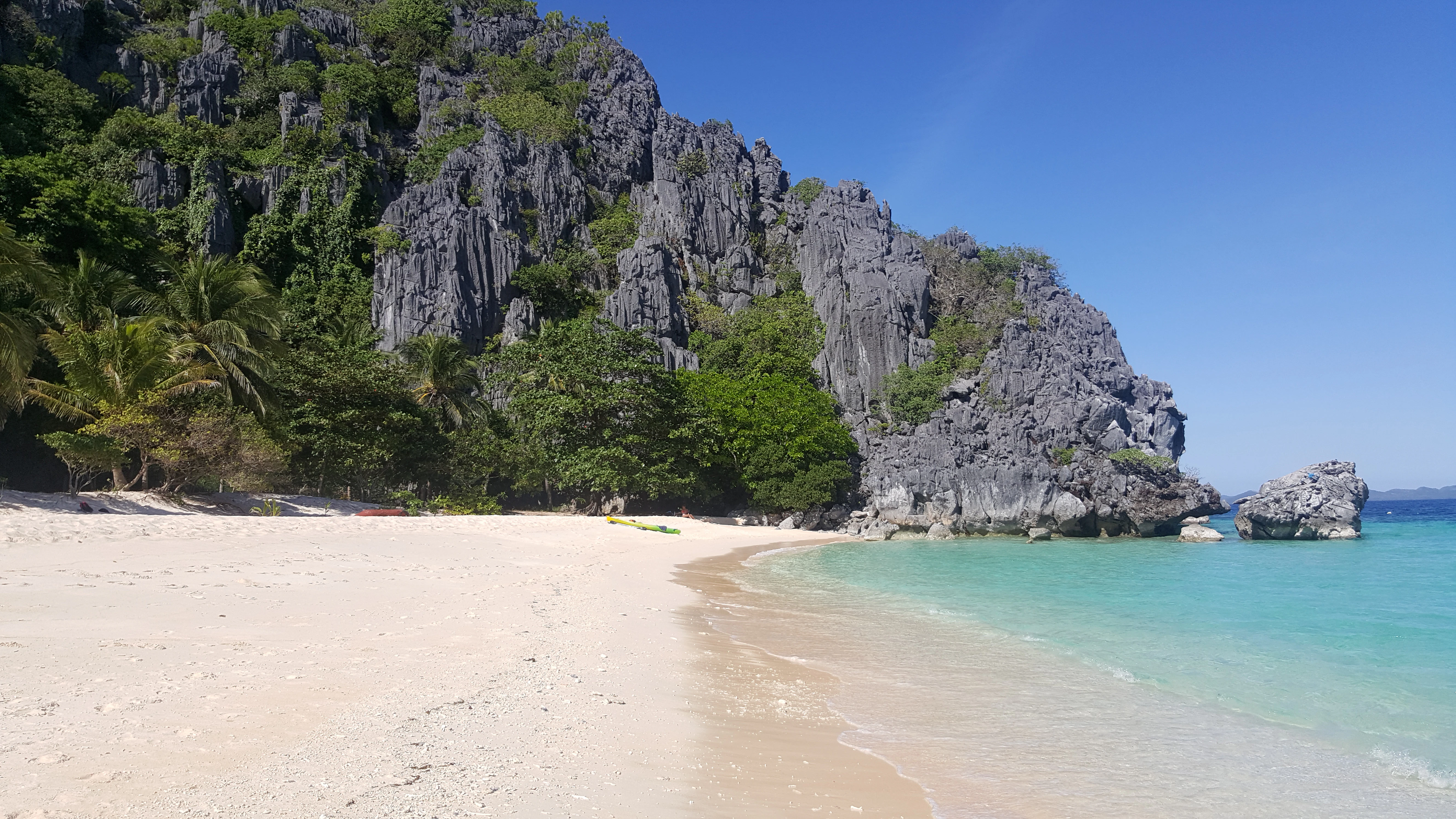 brown sand beach near green mountain under blue sky during daytime