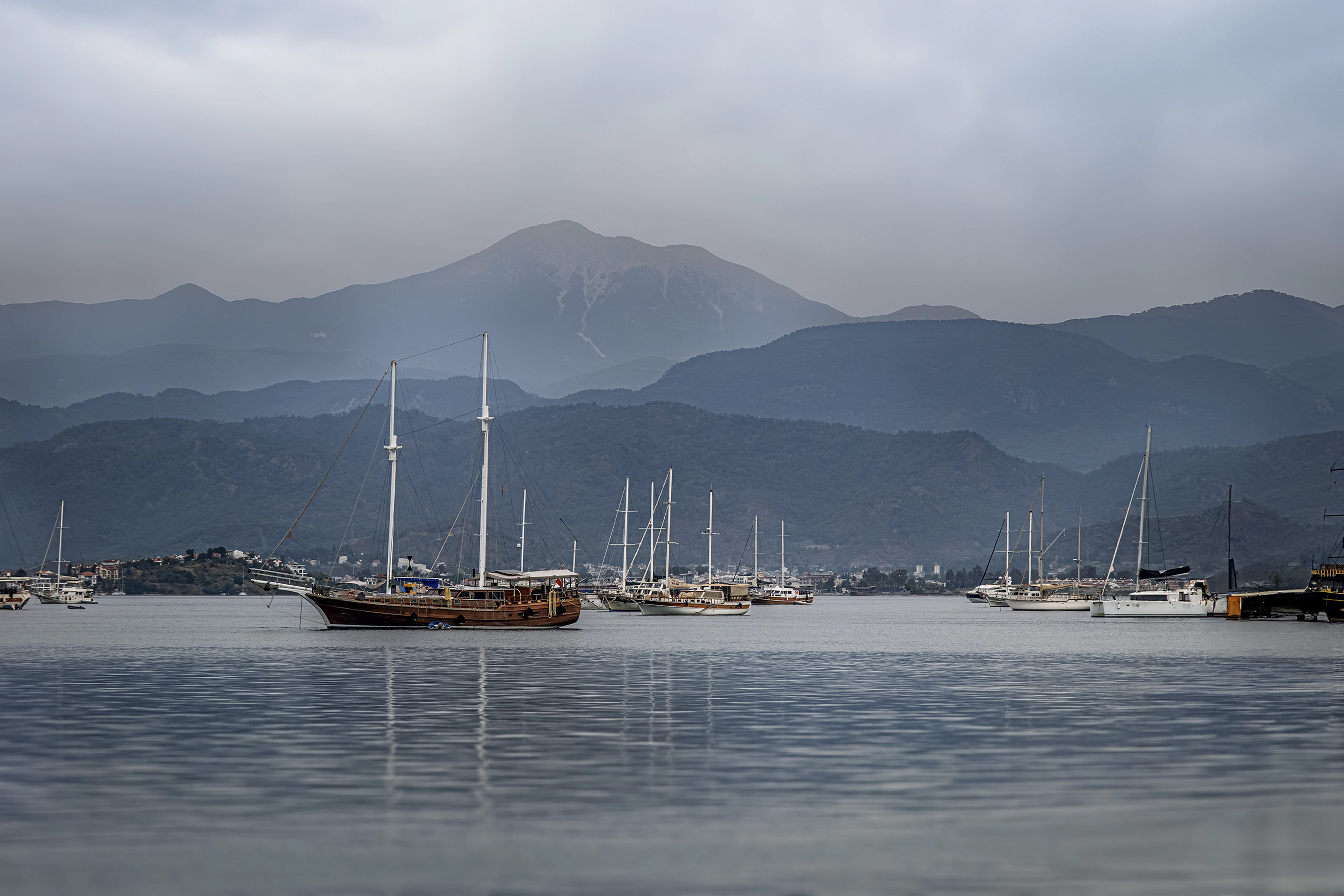 Sailboats anchored in a bay with mountains behind.