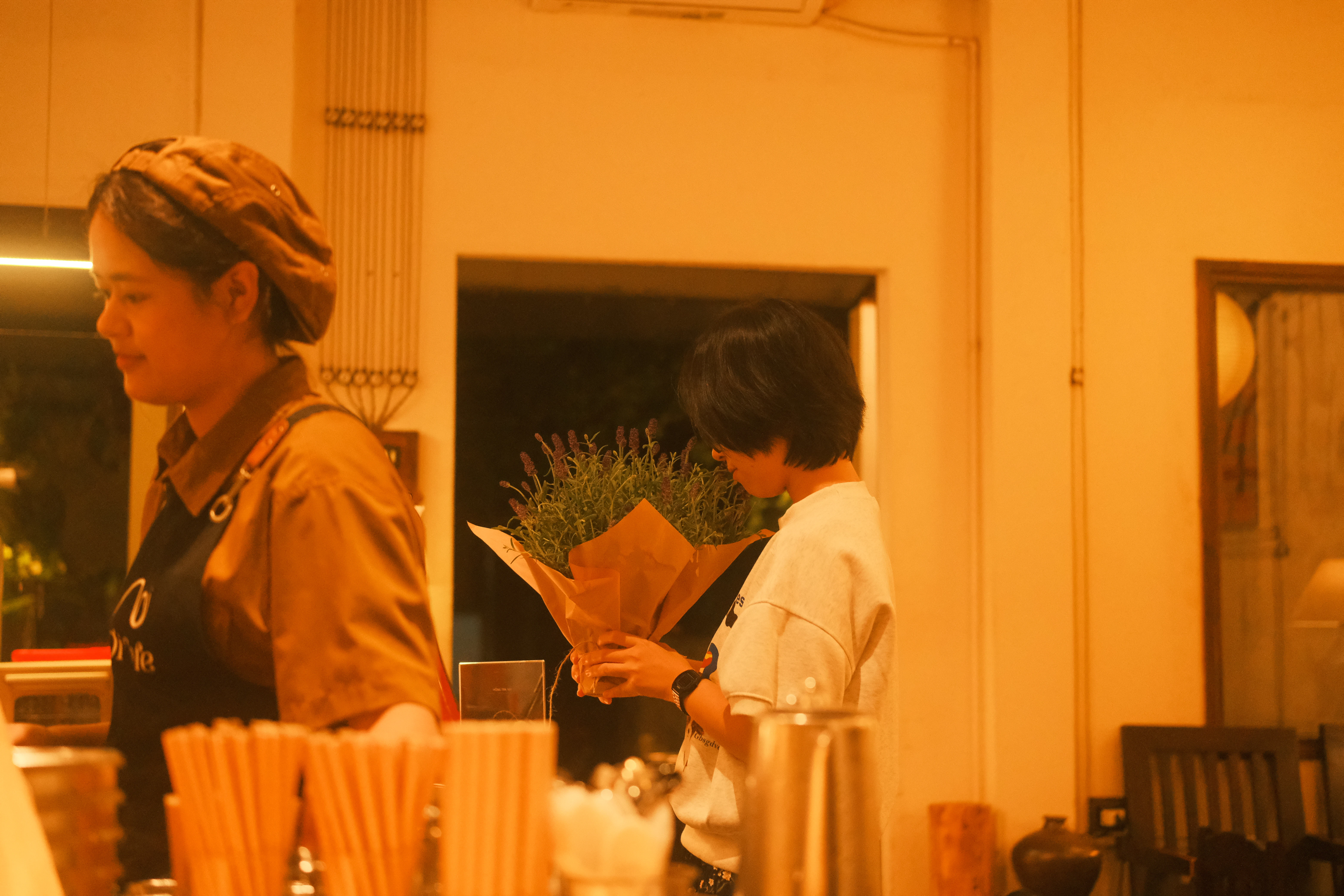 Two people holding a potted plant indoors.