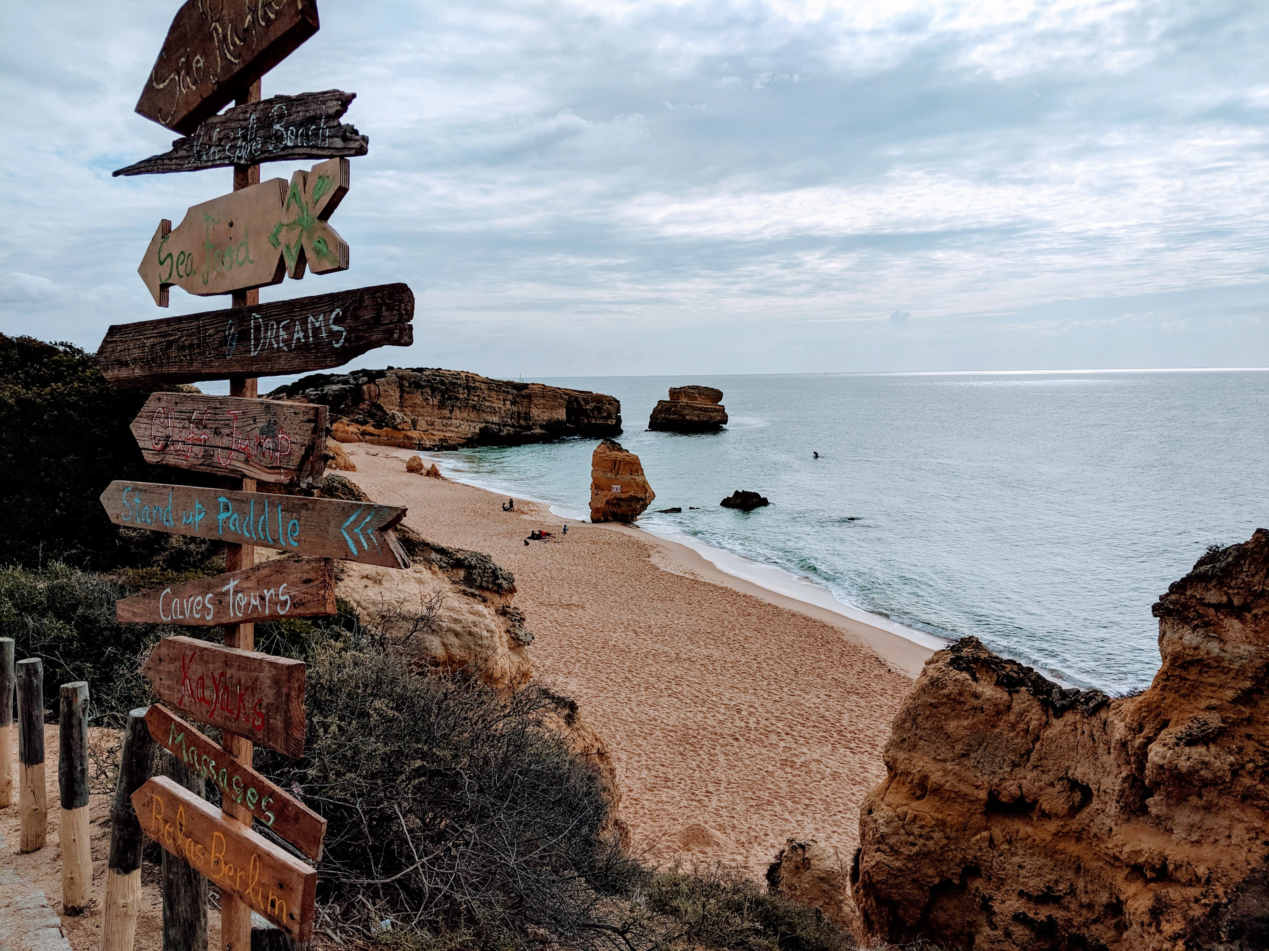 brown wooden direction sign on seashore during daytime