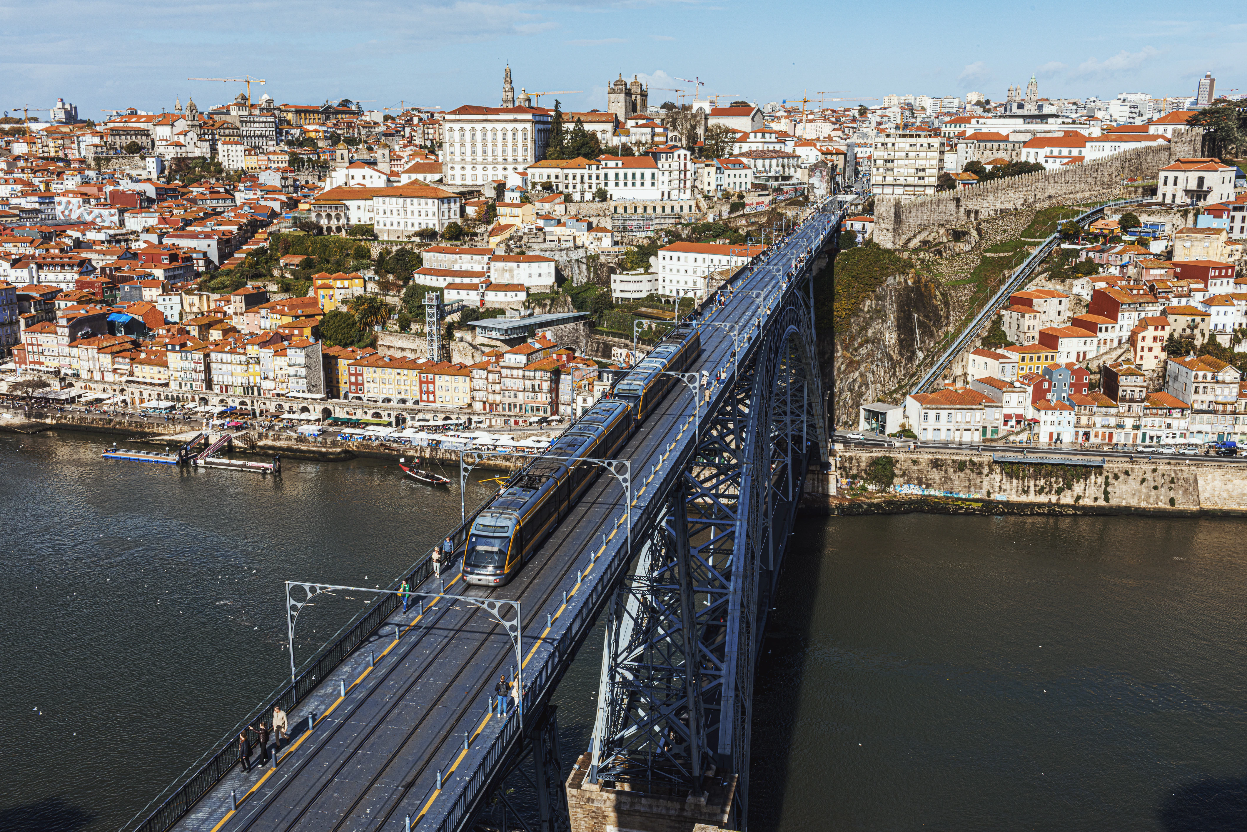 Train crossing a large metal bridge over a river.