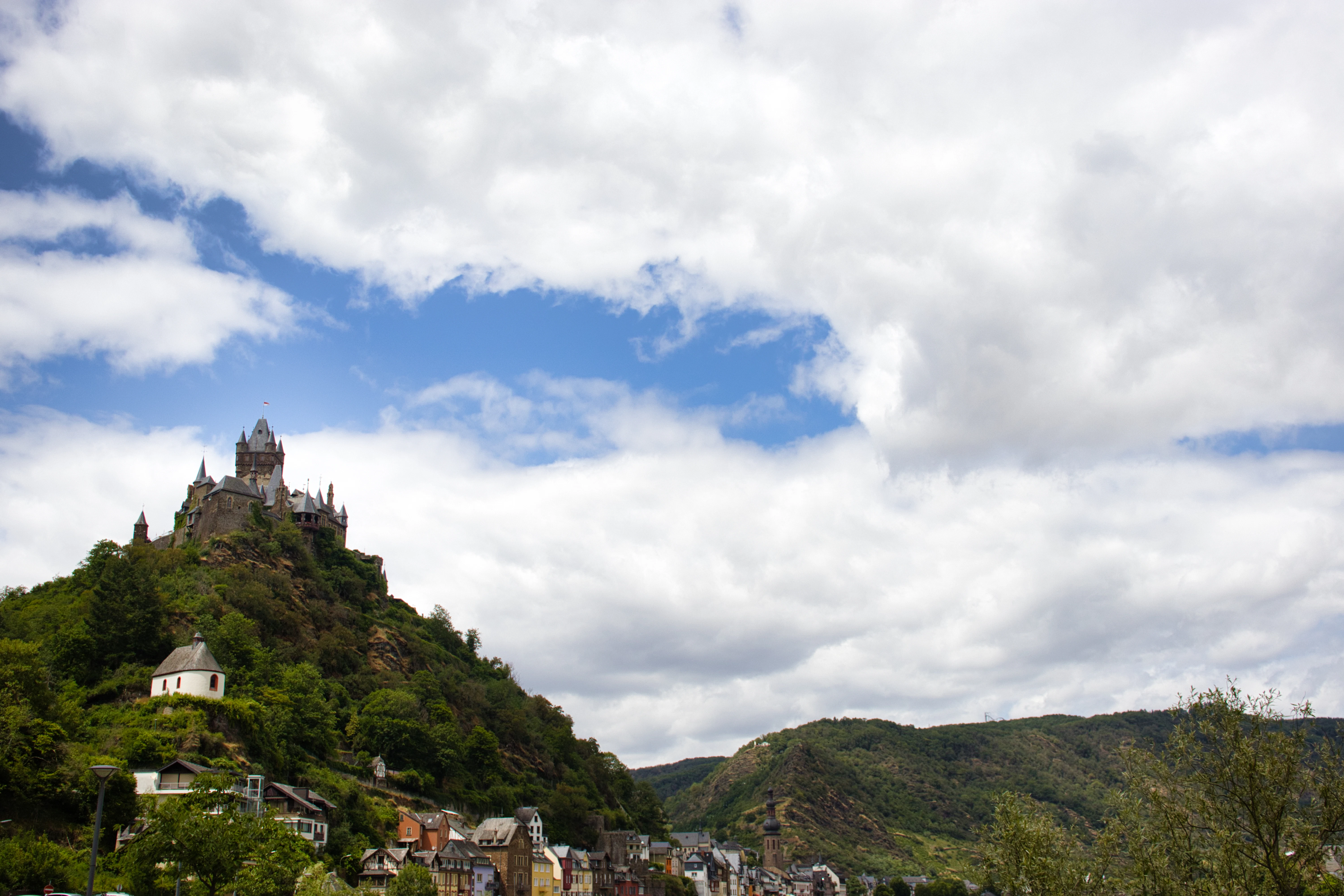 Castle perched on a lush green hillside under cloudy sky