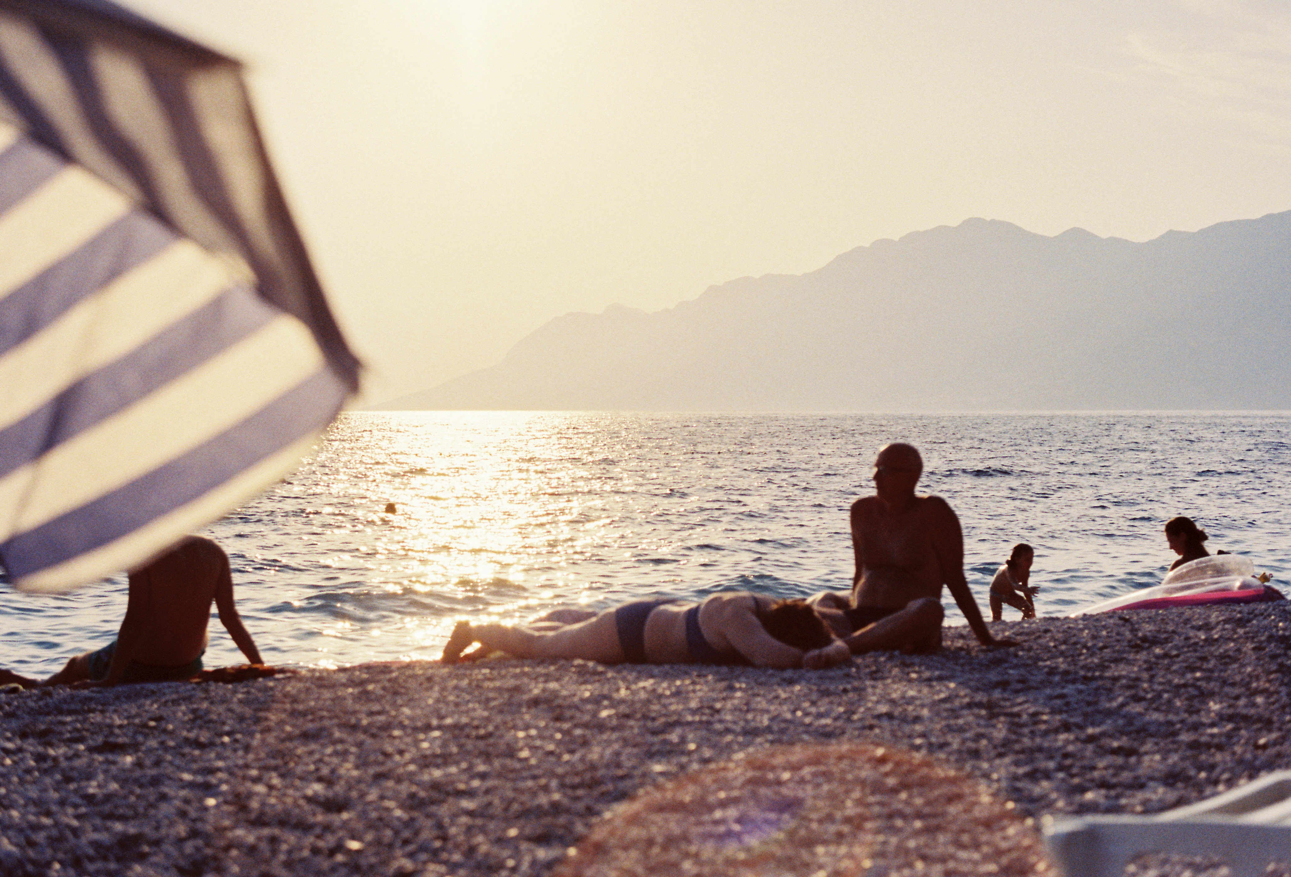 A group of people sitting on top of a beach next to the ocean