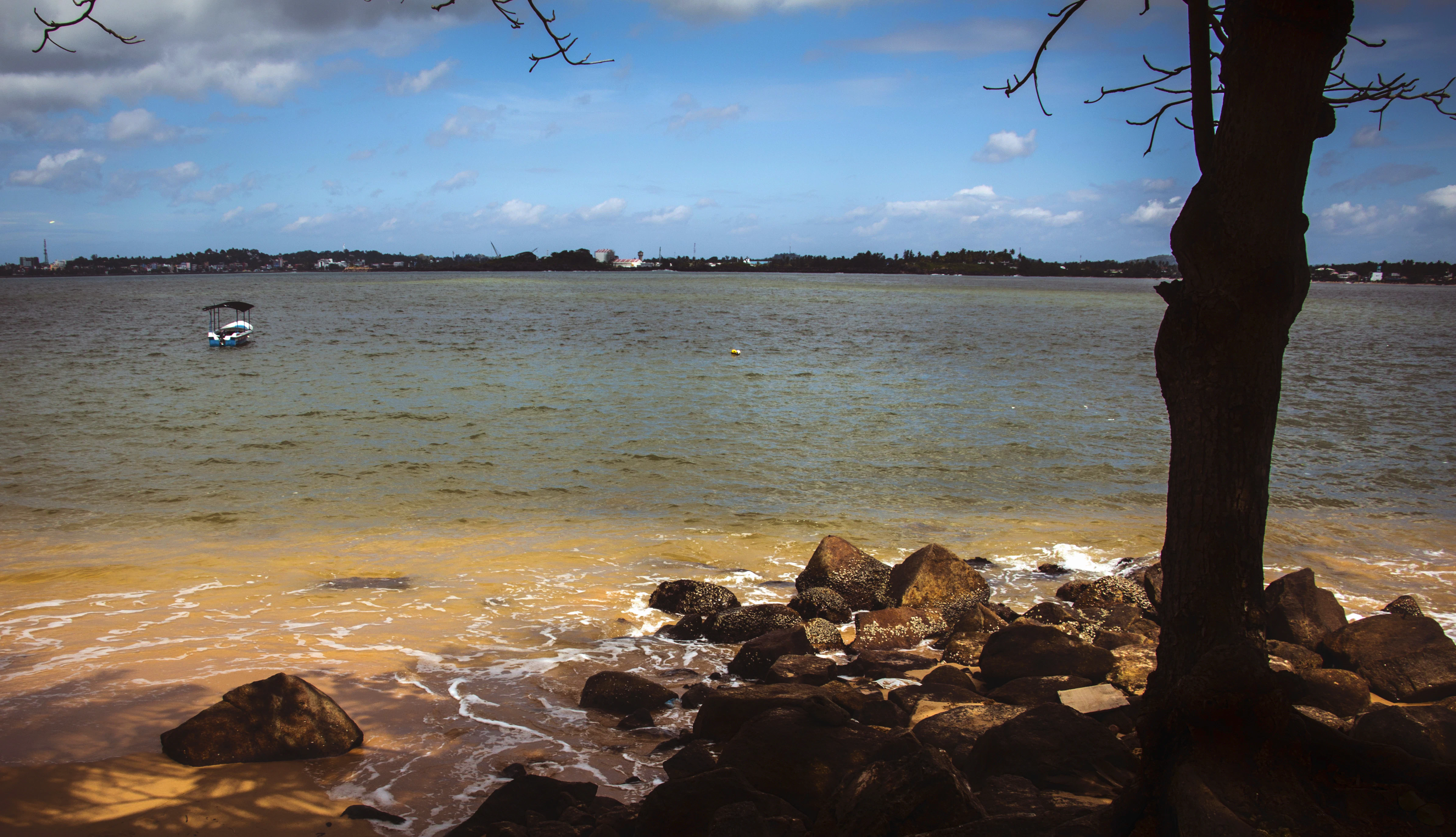 Calm water with a distant boat and rocky shore.