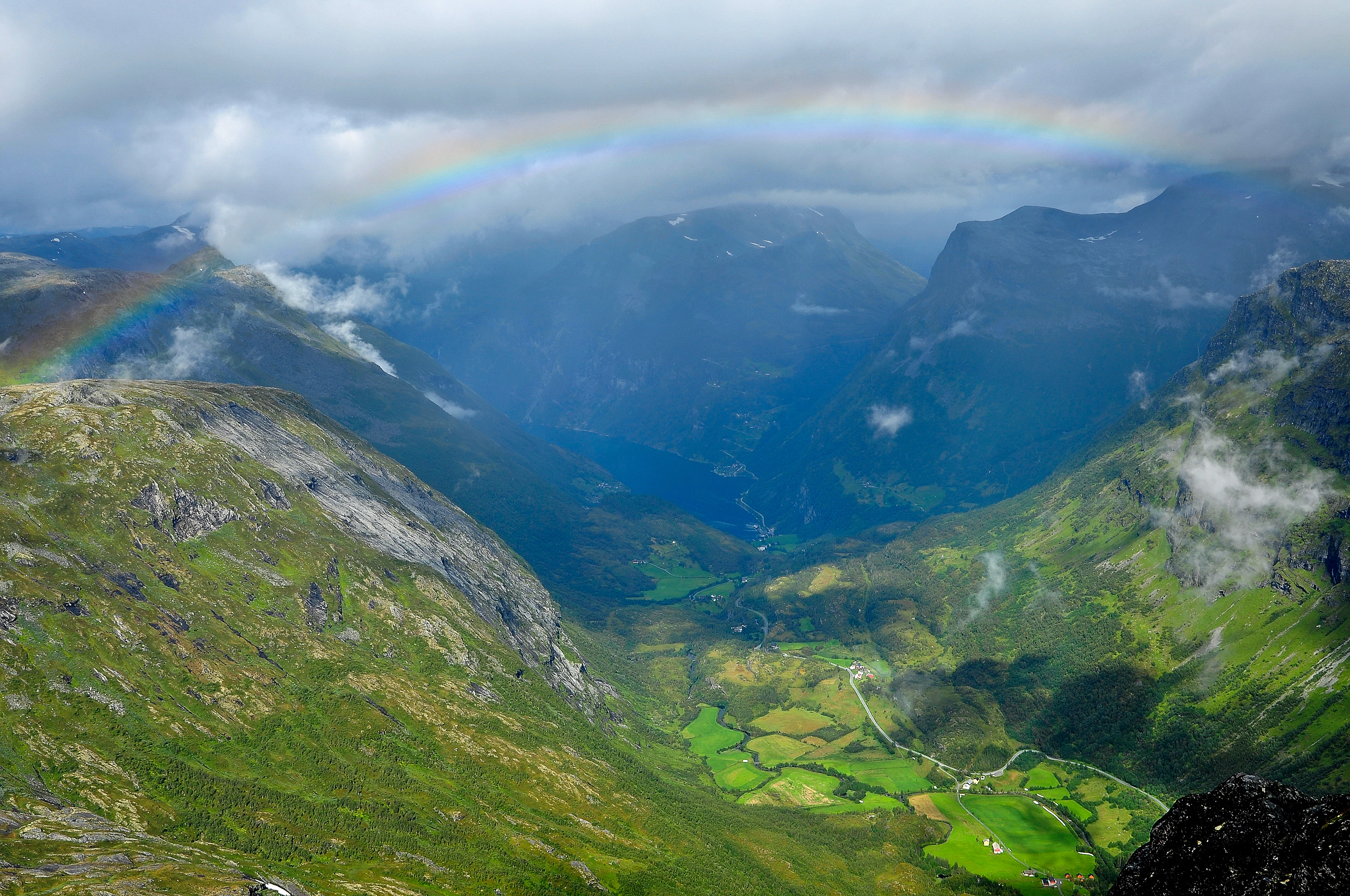 a rainbow in the sky over a valley