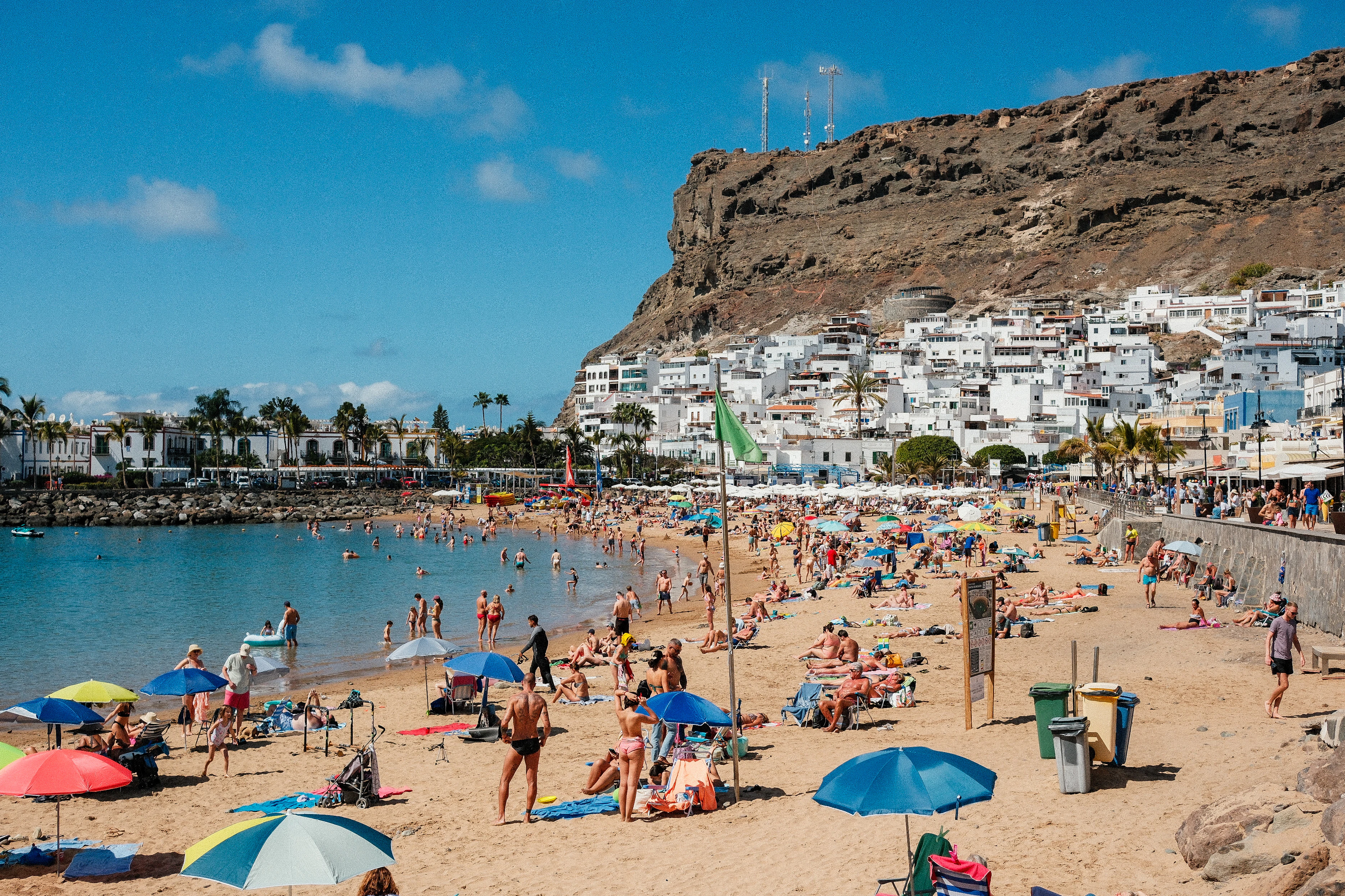 A crowded beach with many people and umbrellas