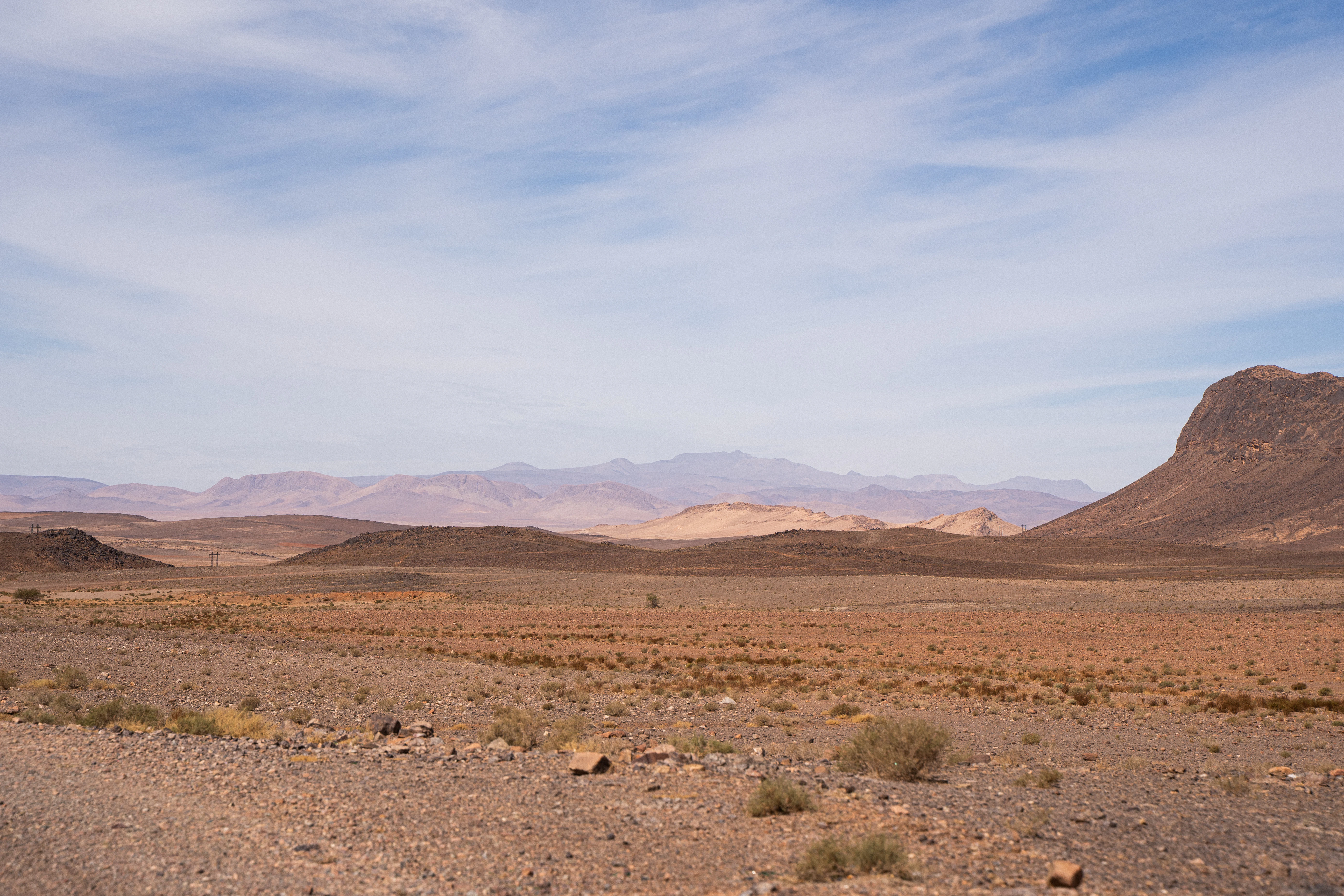 Arid desert landscape with distant mountains under a cloudy sky.