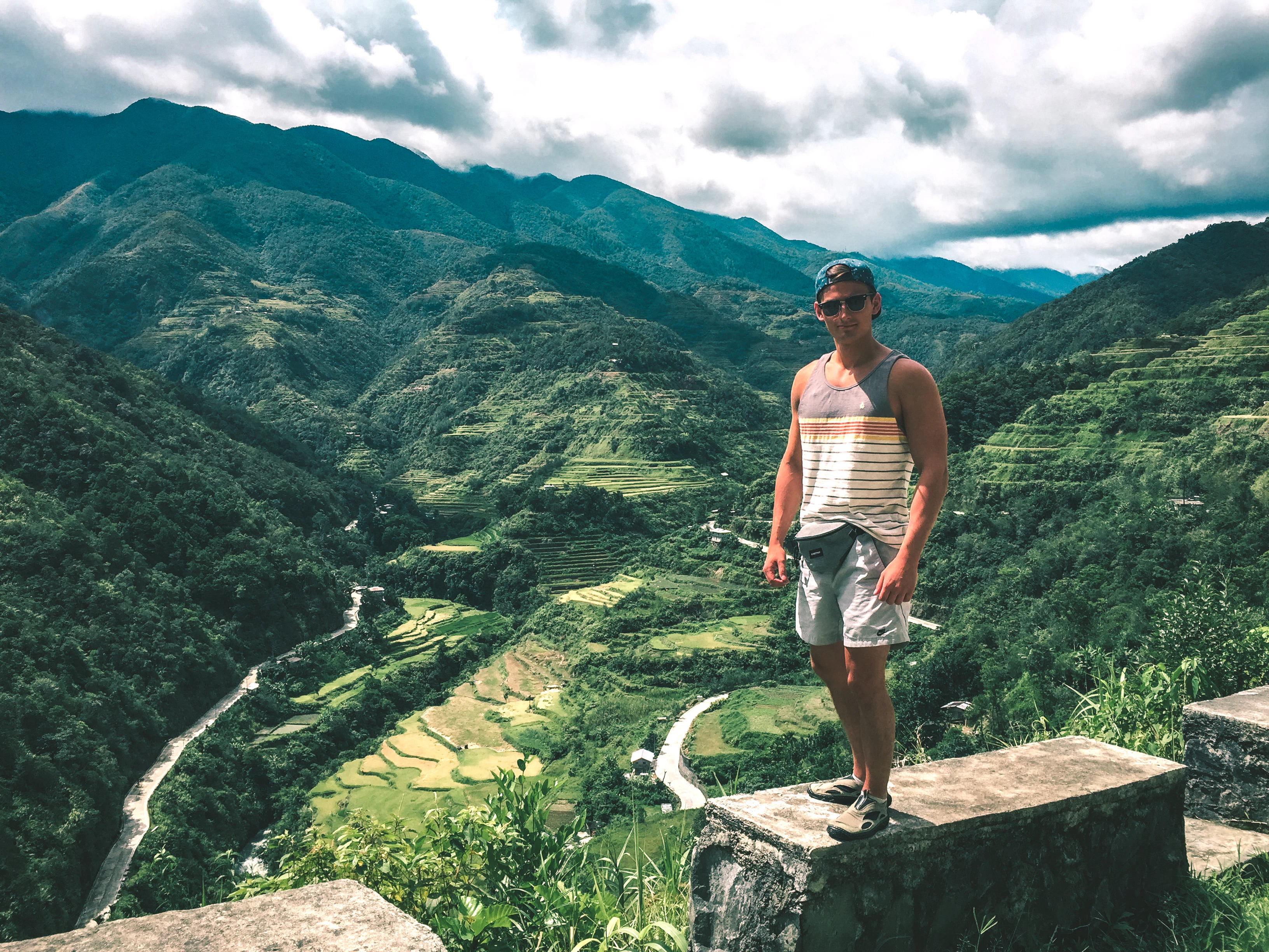 man wearing gray and white striped sleeveless shirt standing uphill during daytime