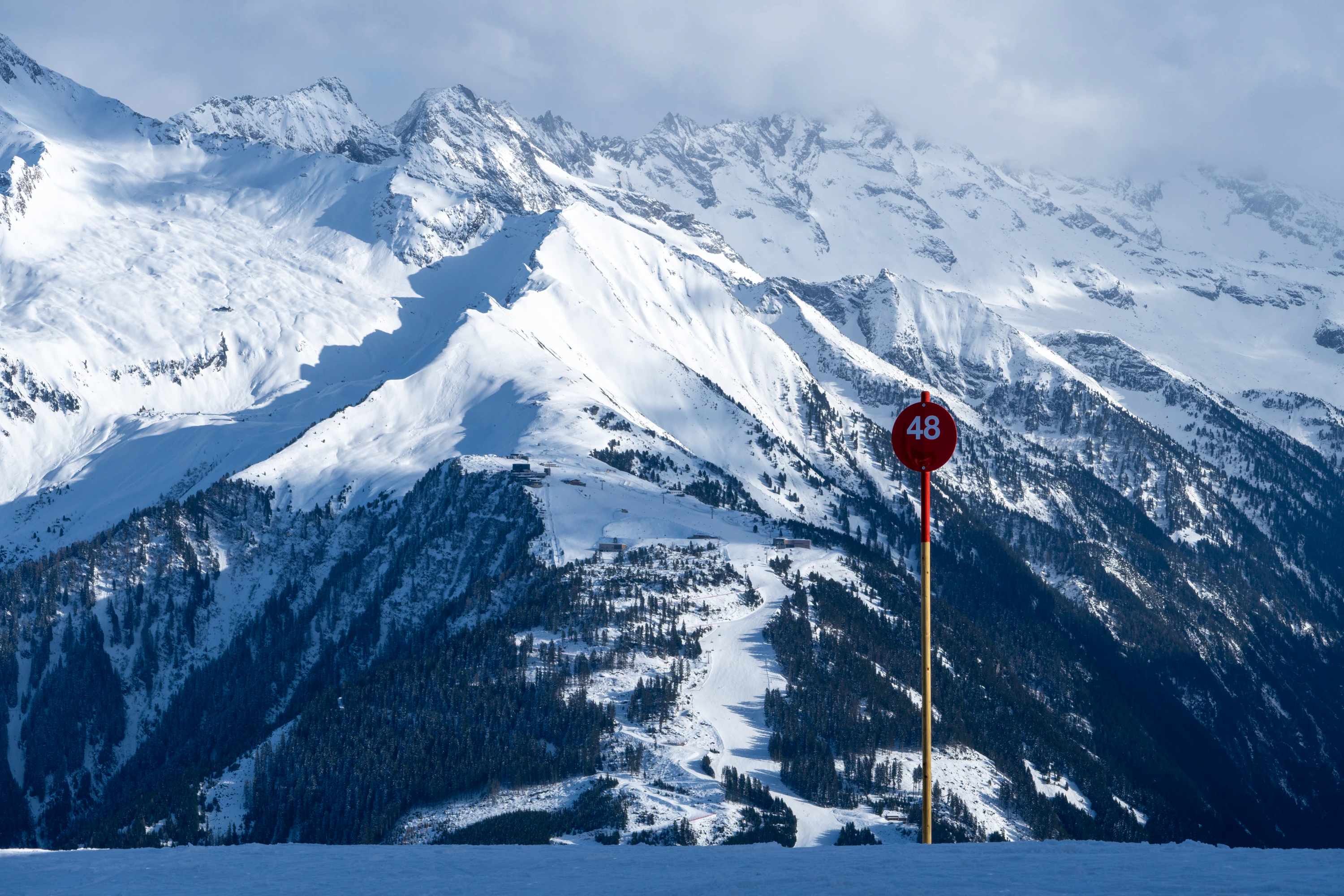 a red stop sign sitting on the side of a snow covered mountain