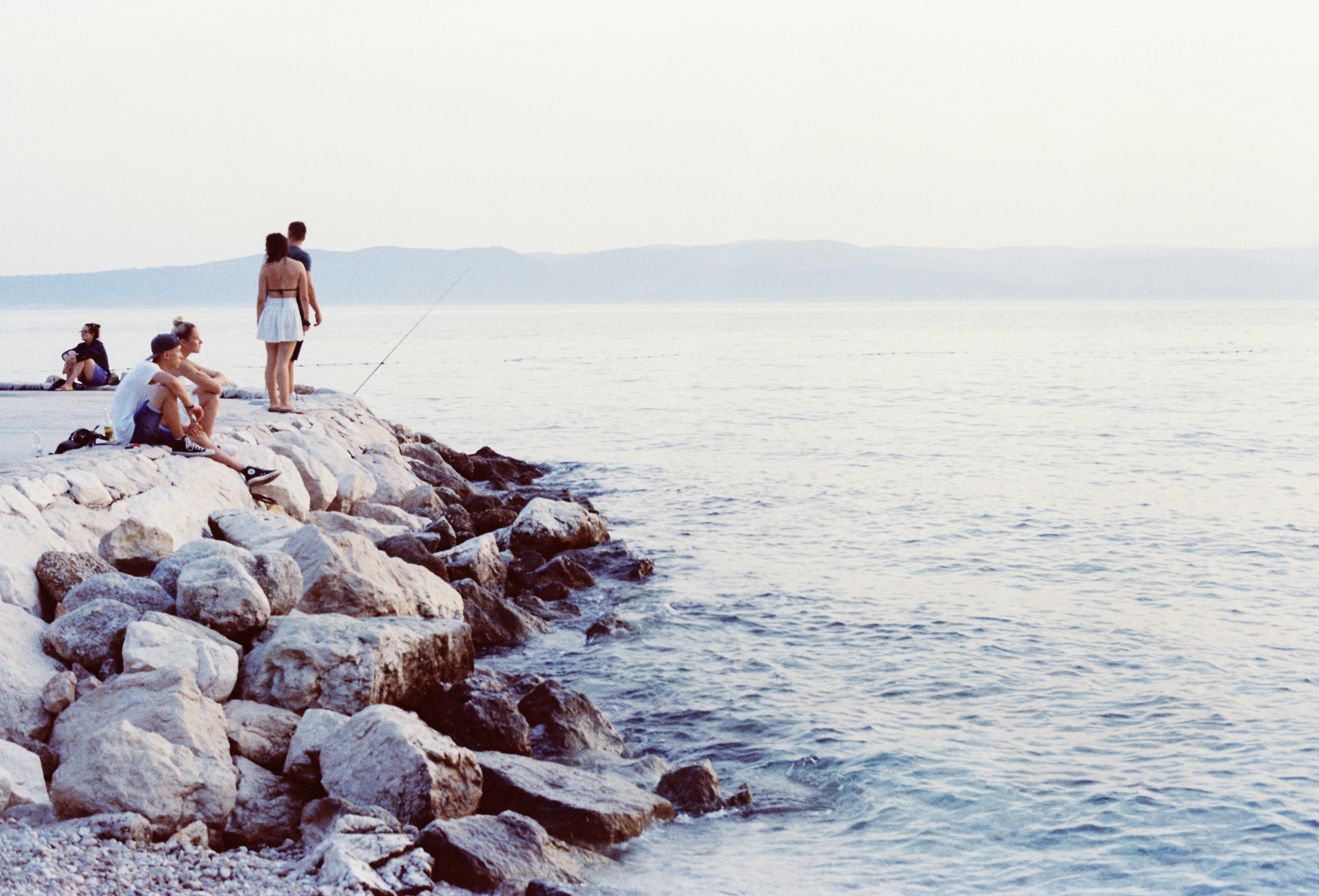 A group of people standing on top of a rocky shore