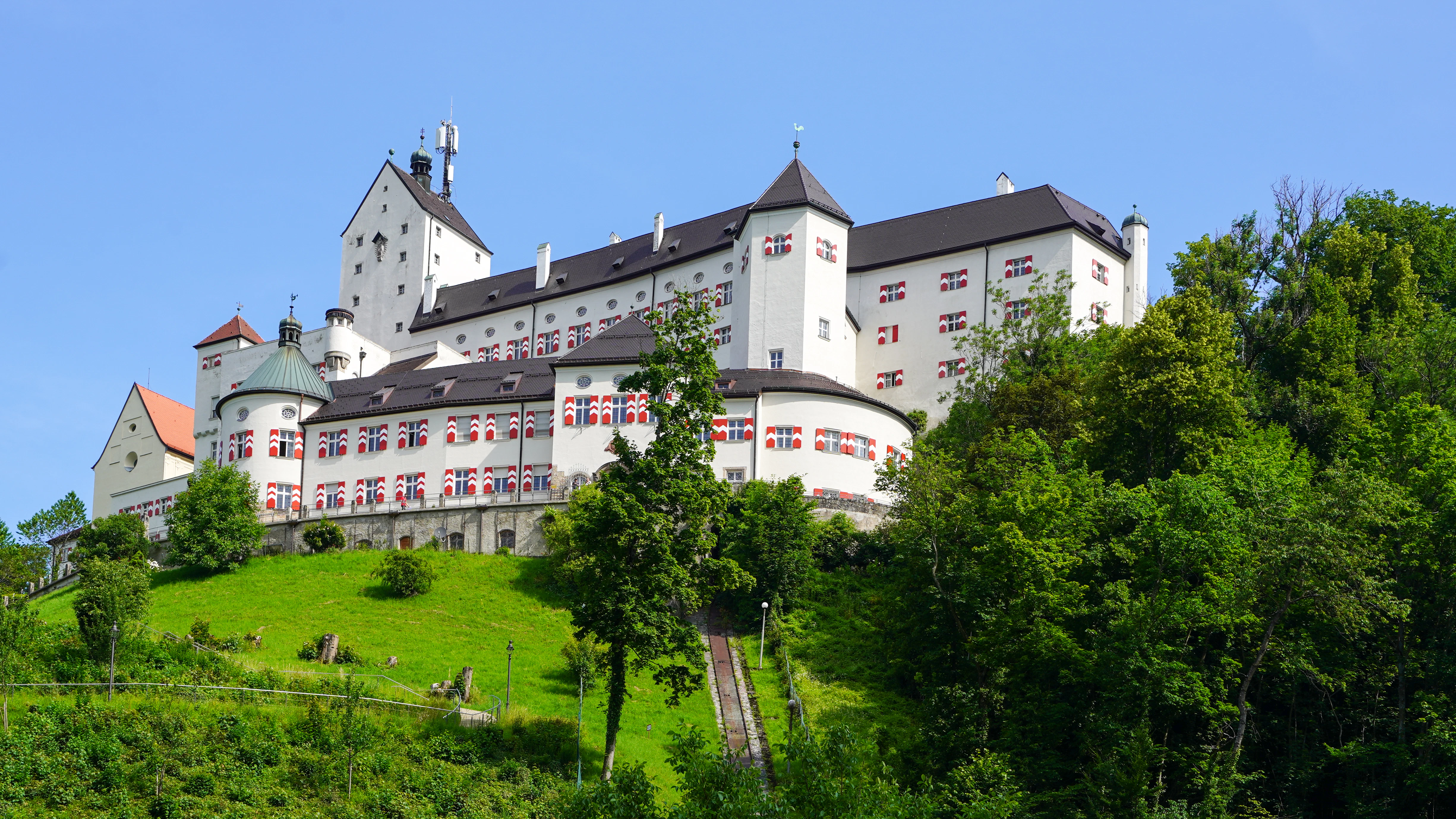 A large white castle sits on a green hill.