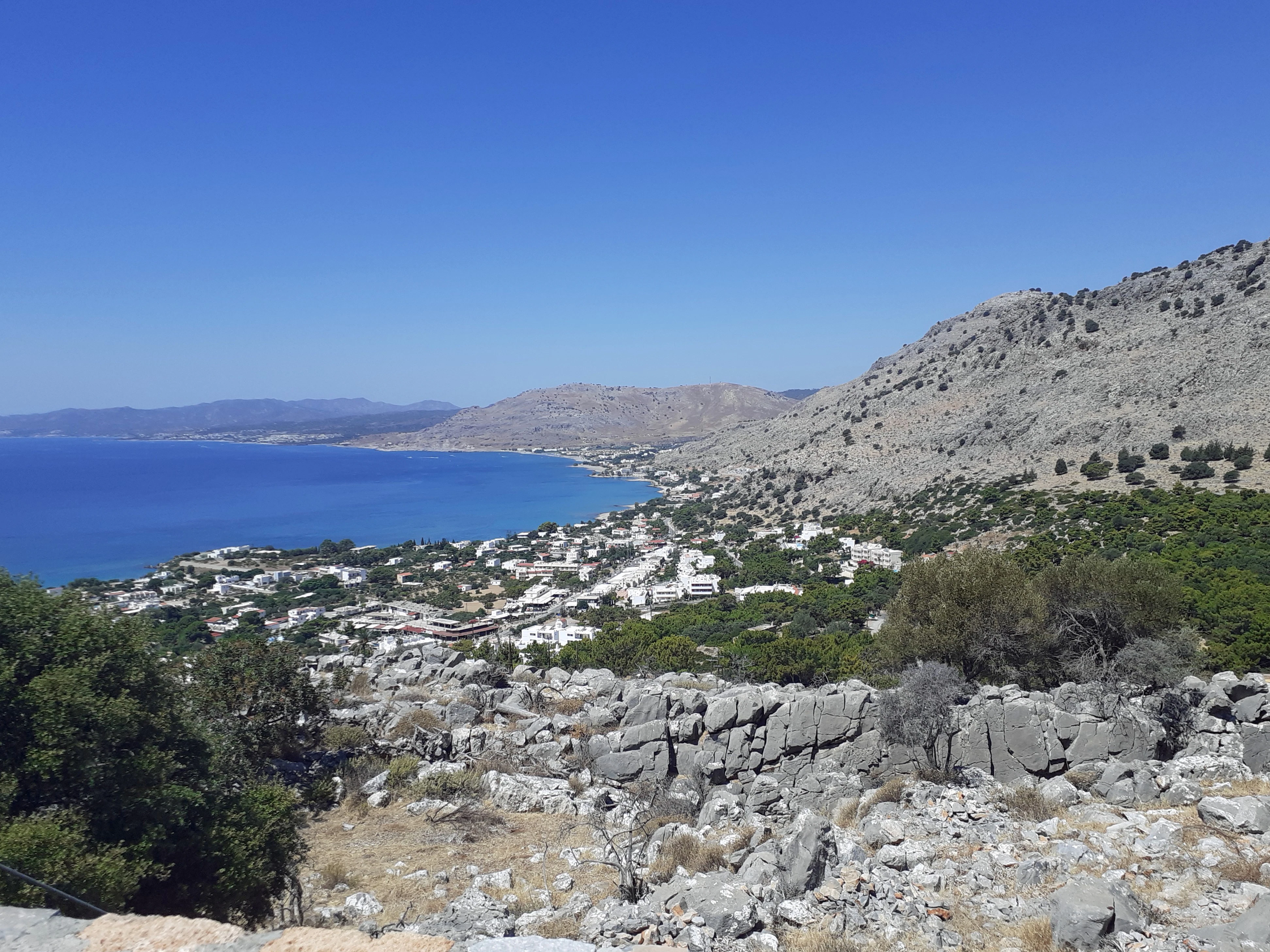green and brown mountain beside blue sea under blue sky during daytime