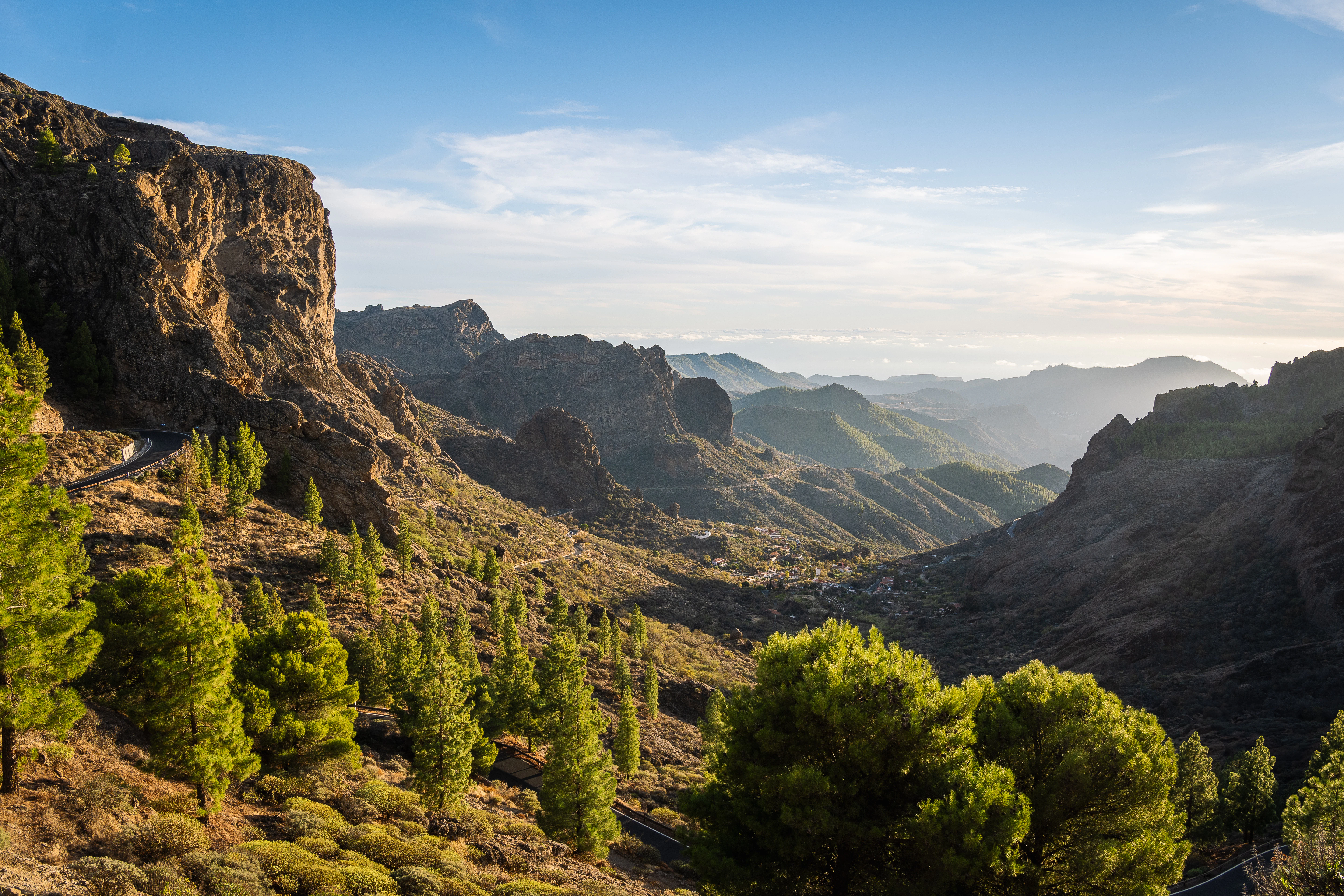 a scenic view of mountains and trees on a sunny day