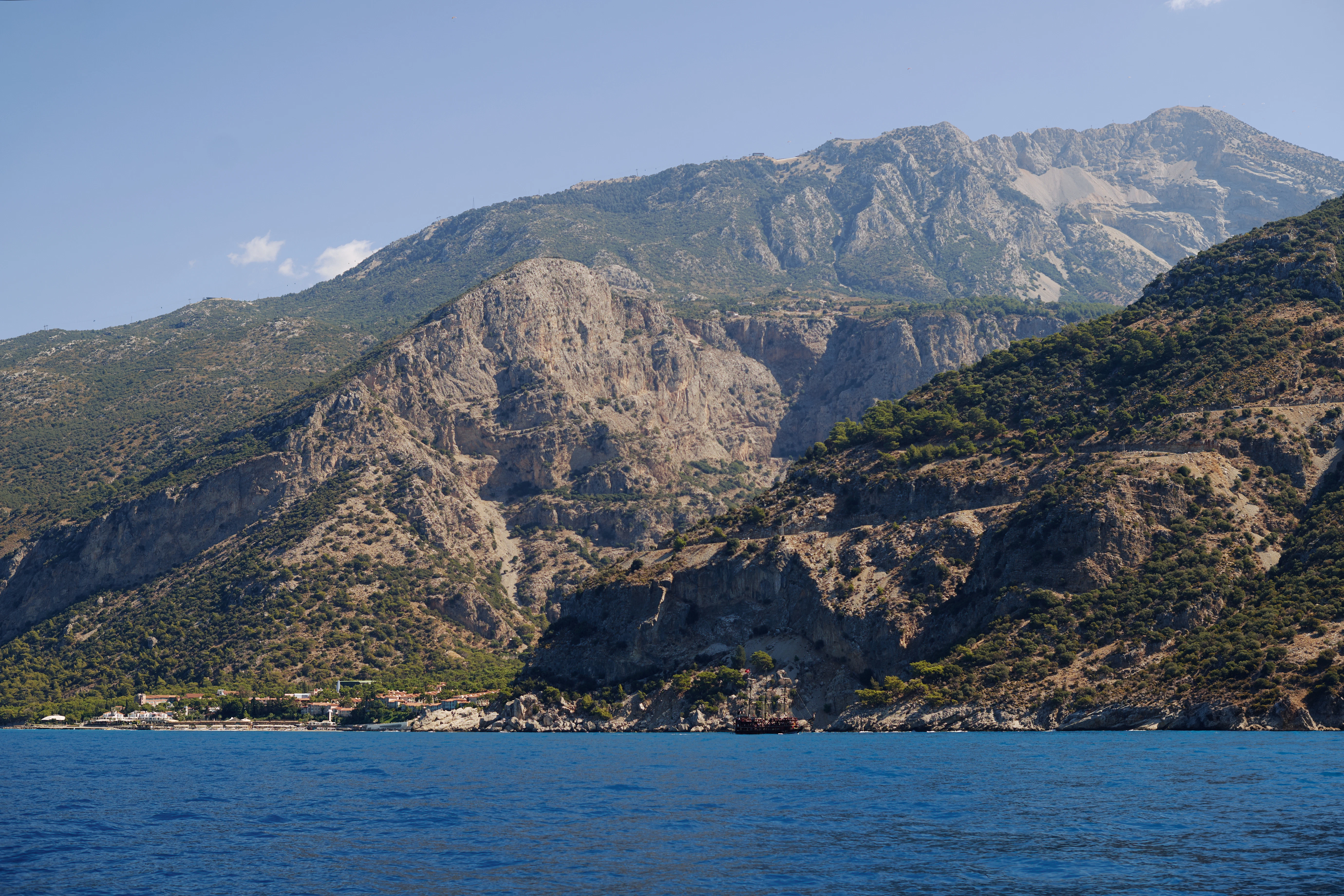 Mountains rise from a blue sea under a blue sky.