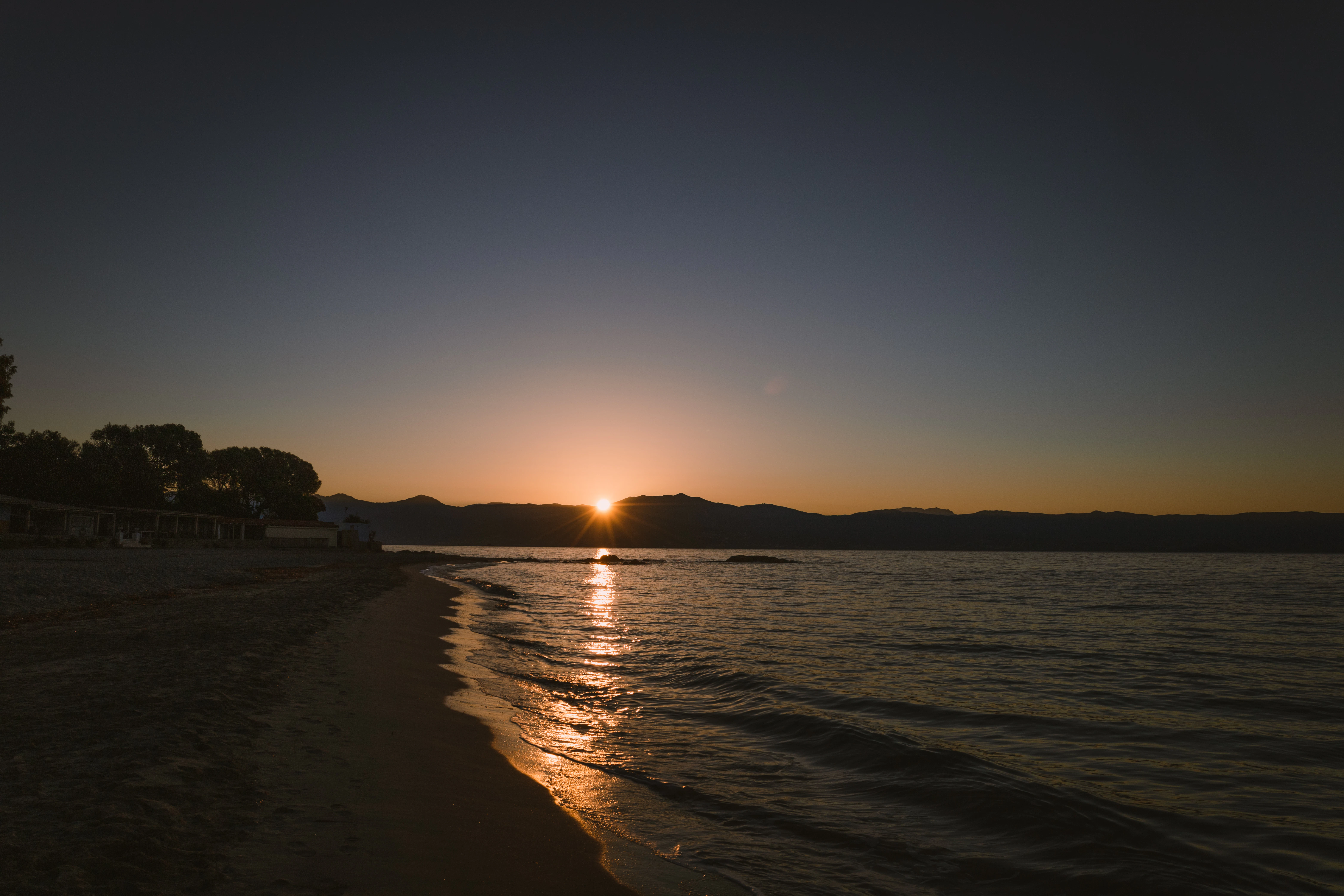 a beach with a body of water and a sunset