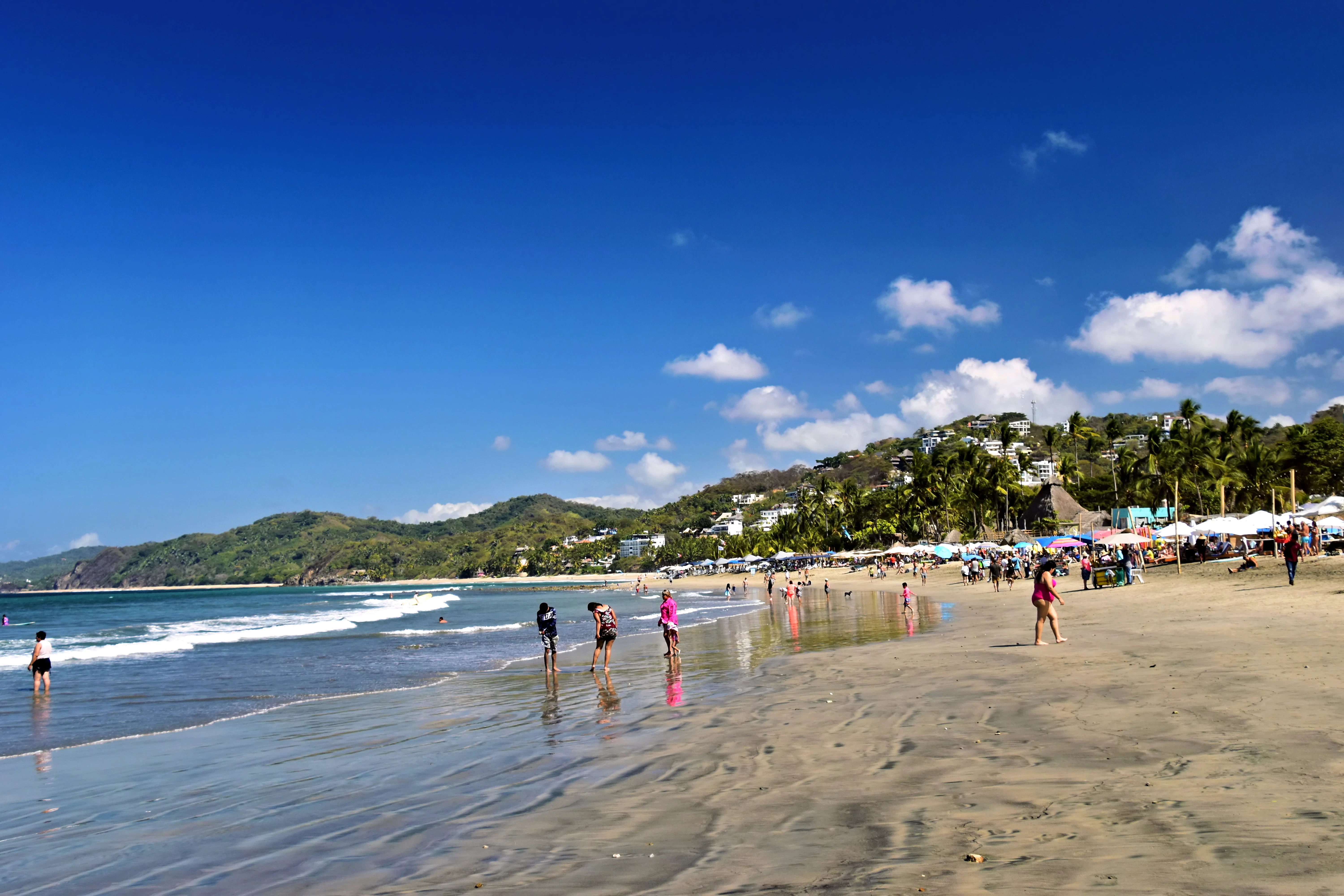 People enjoying a sunny day at a crowded beach.