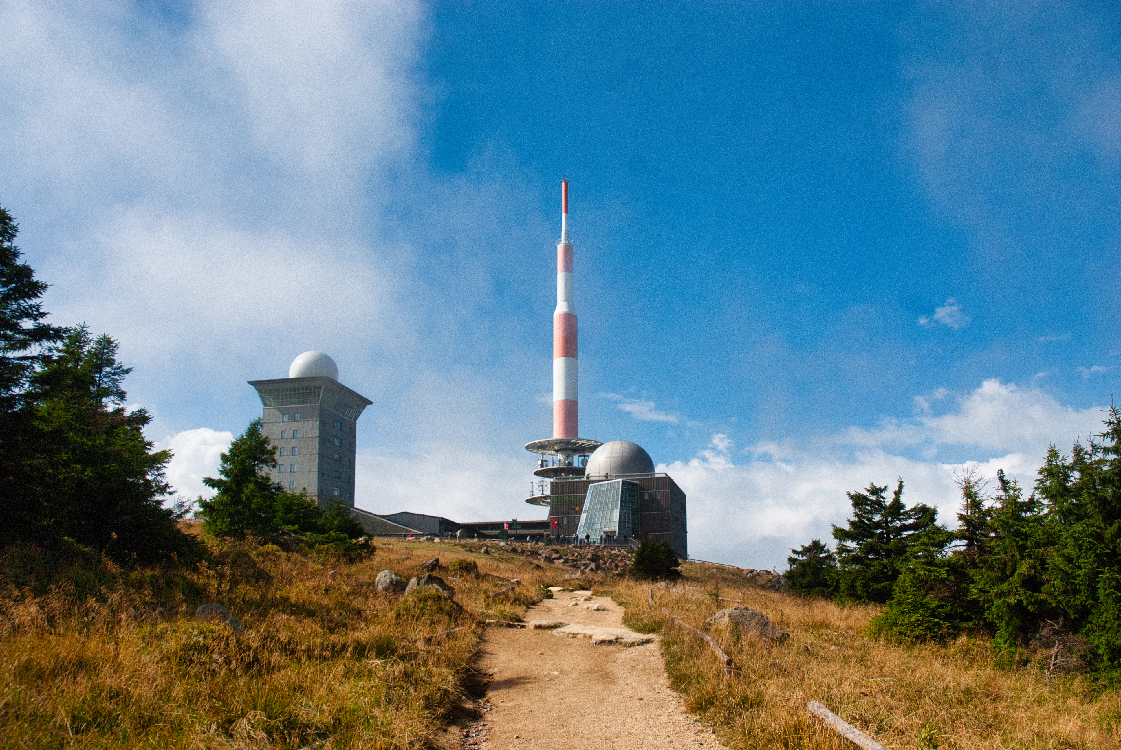 Broadcasting tower on a grassy hilltop under blue sky