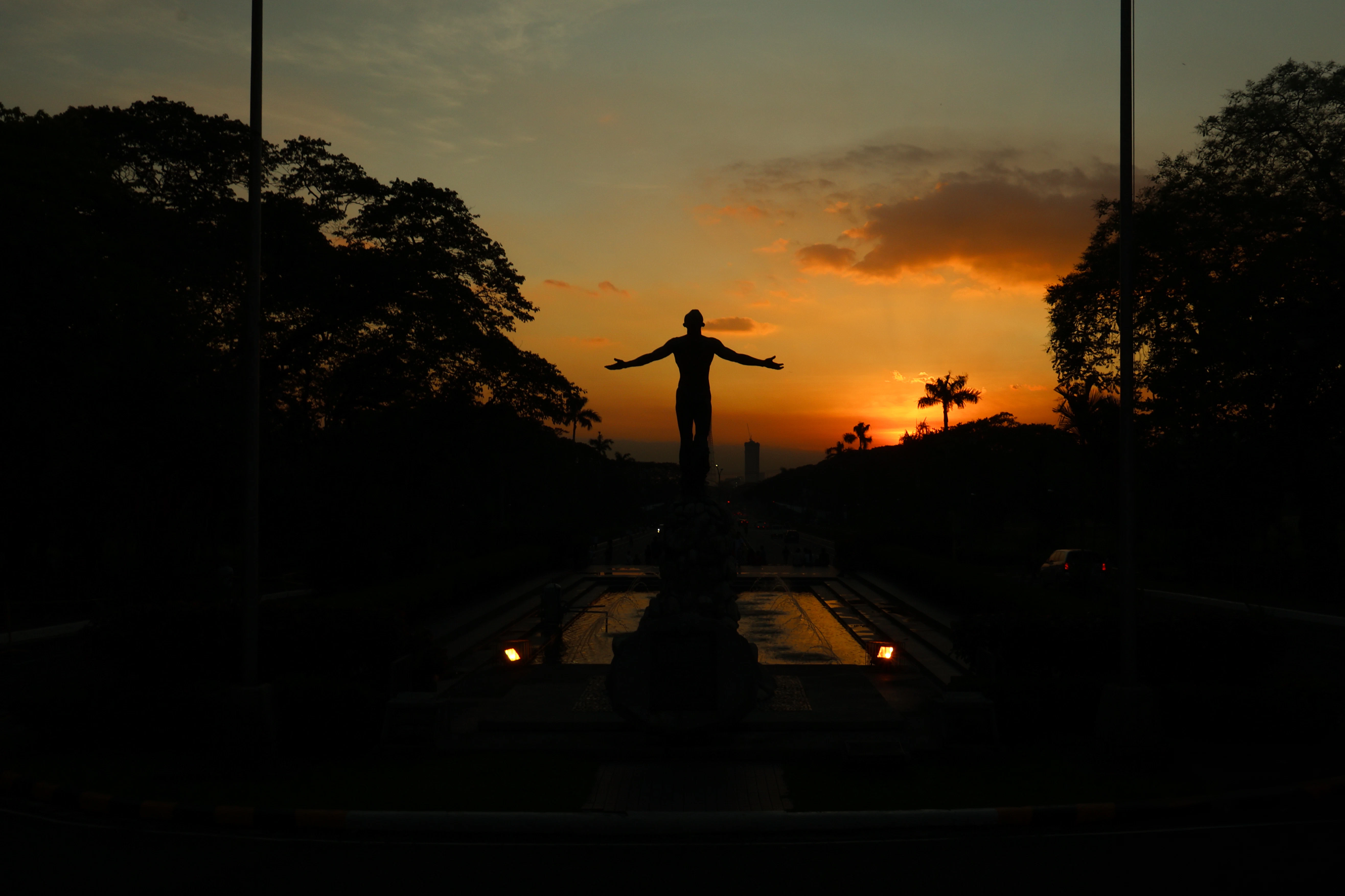A statue silhouetted against a fiery sunset.