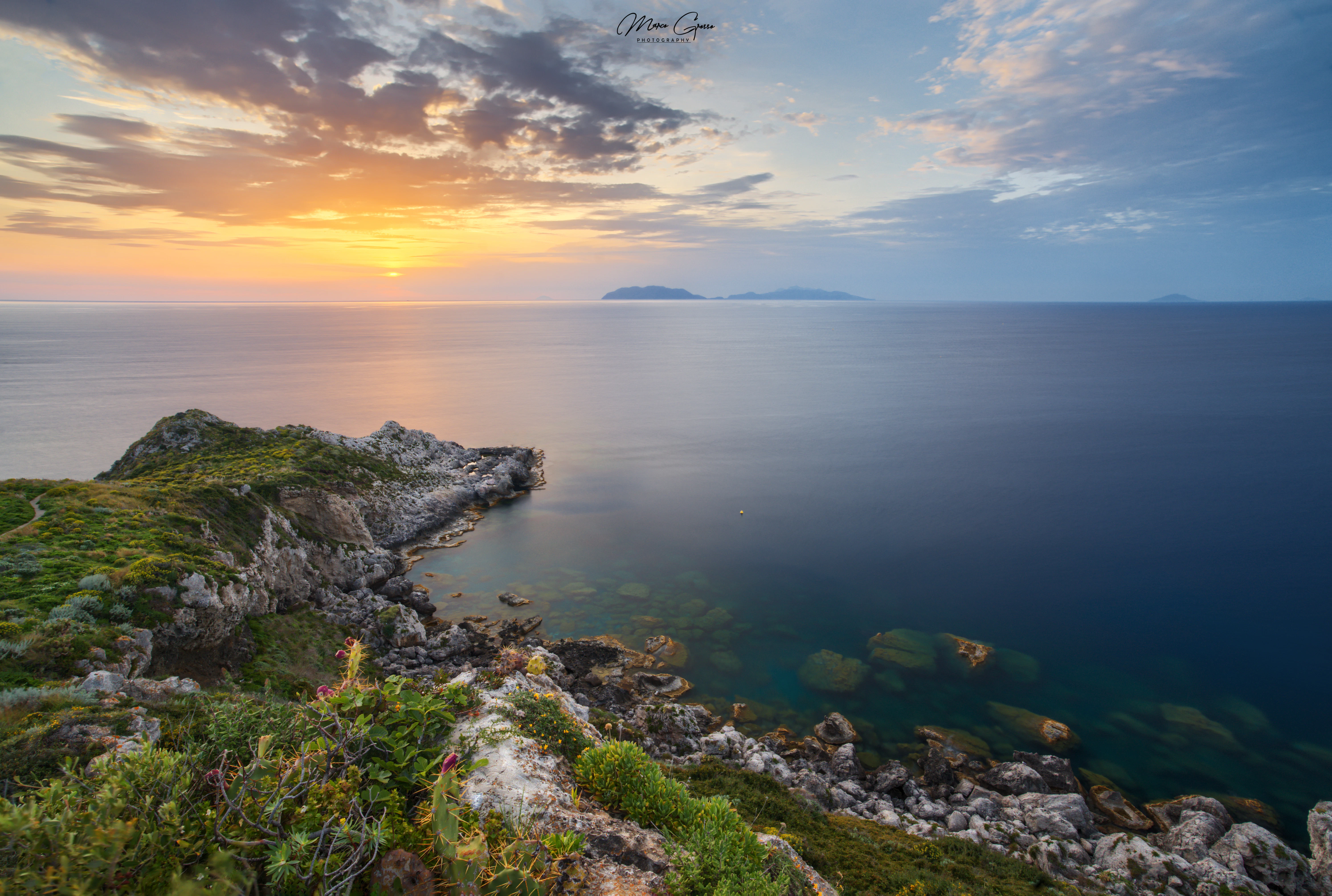 Rocky coastline with calm ocean at sunset