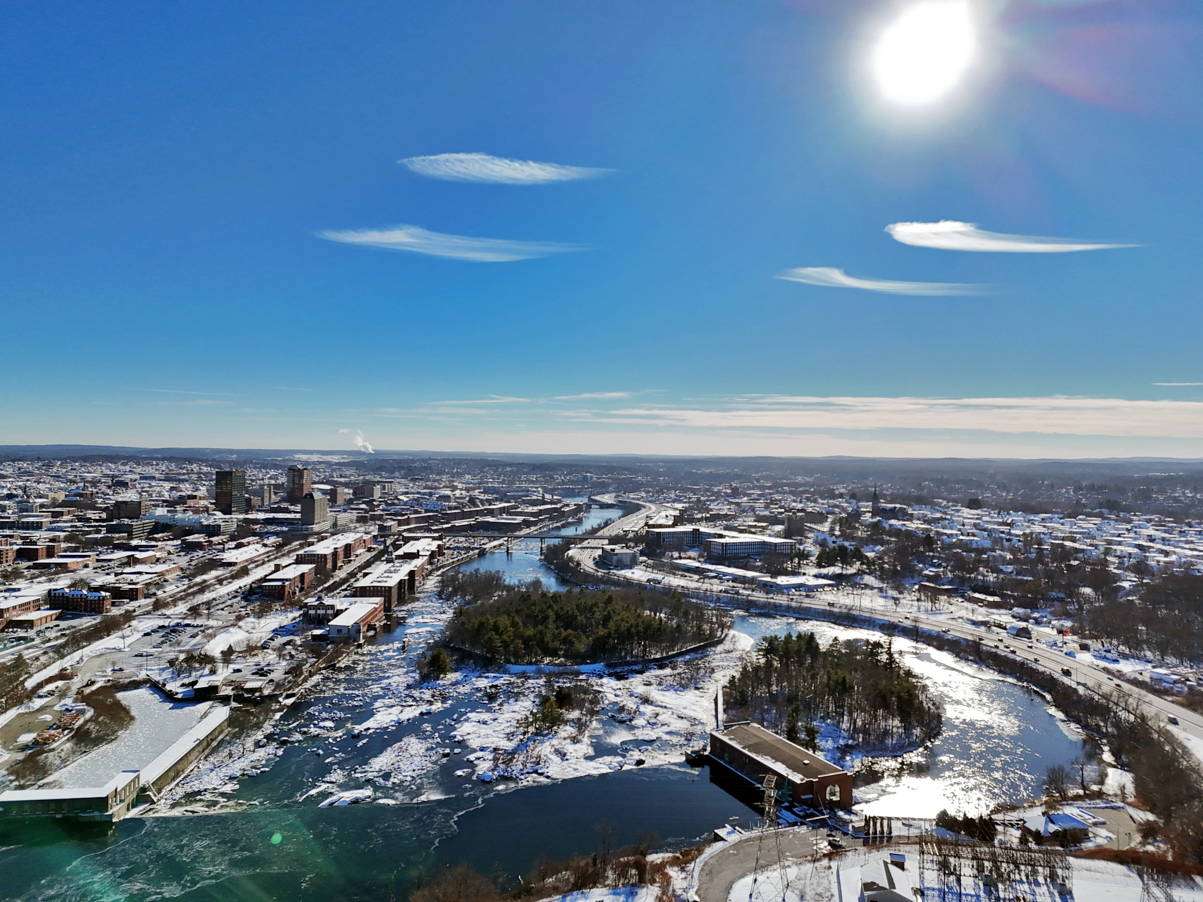 Winter cityscape with a frozen river and bright sun.