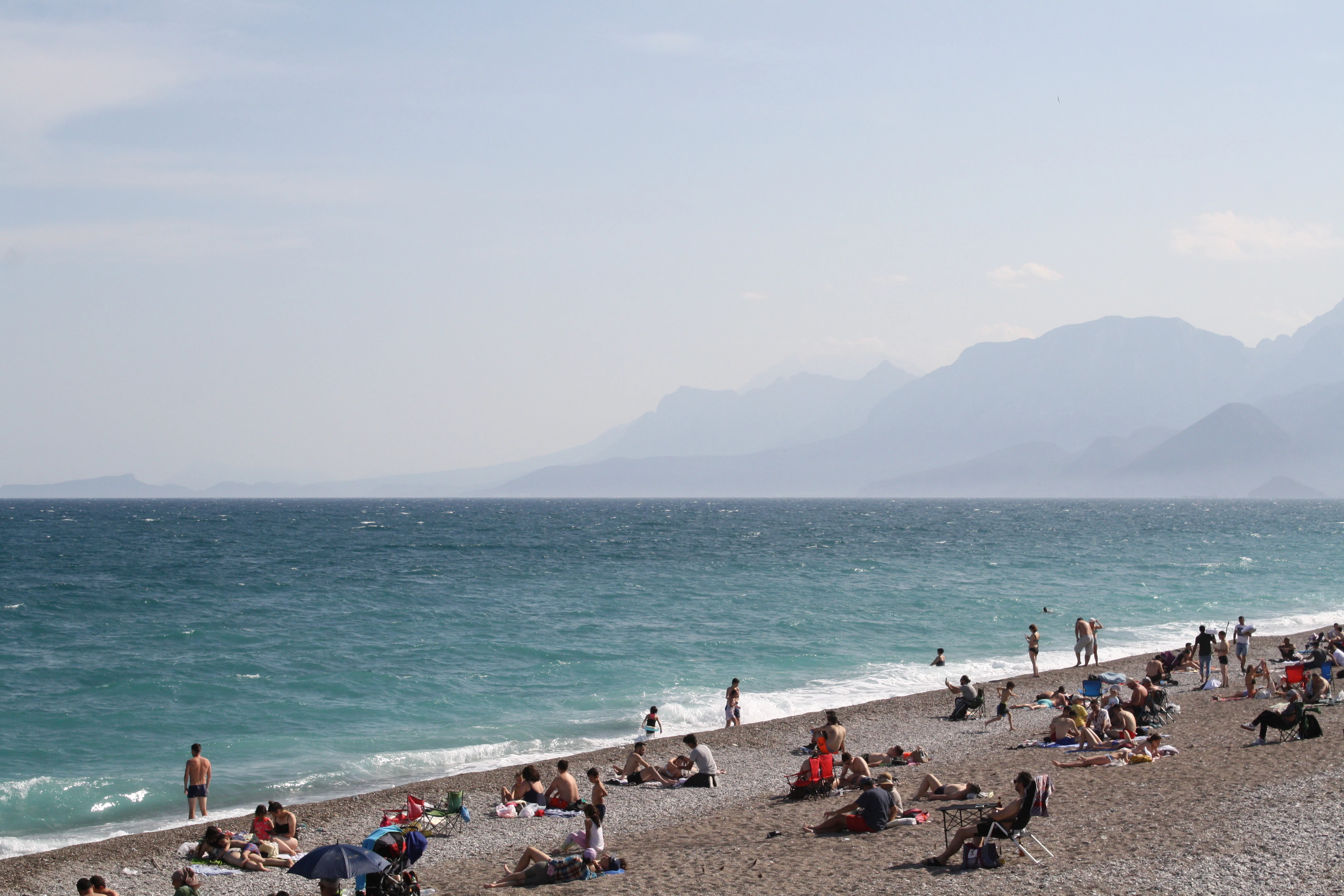 A group of people sitting on top of a beach next to the ocean