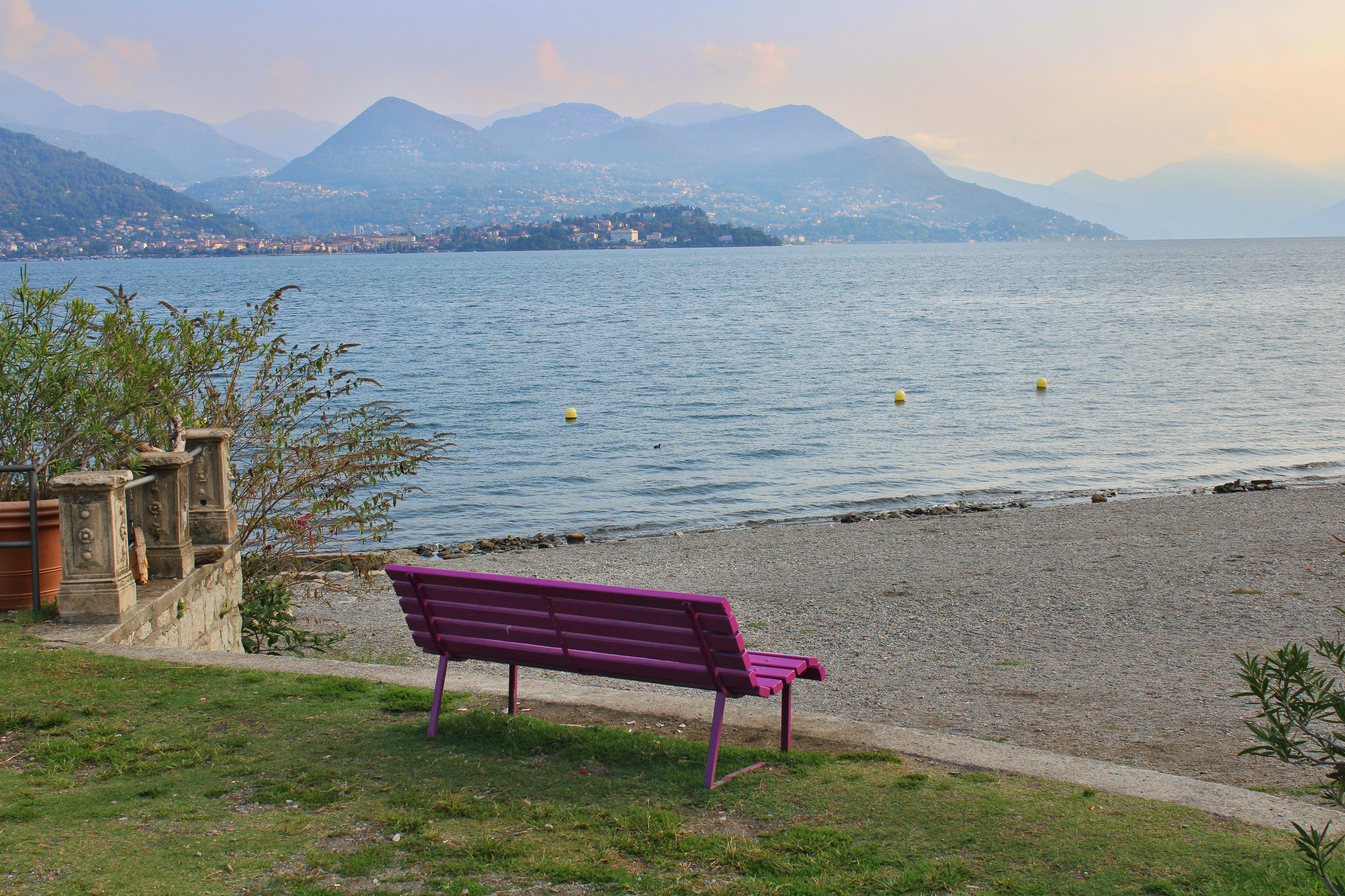 Purple bench overlooks a tranquil lake and distant mountains.