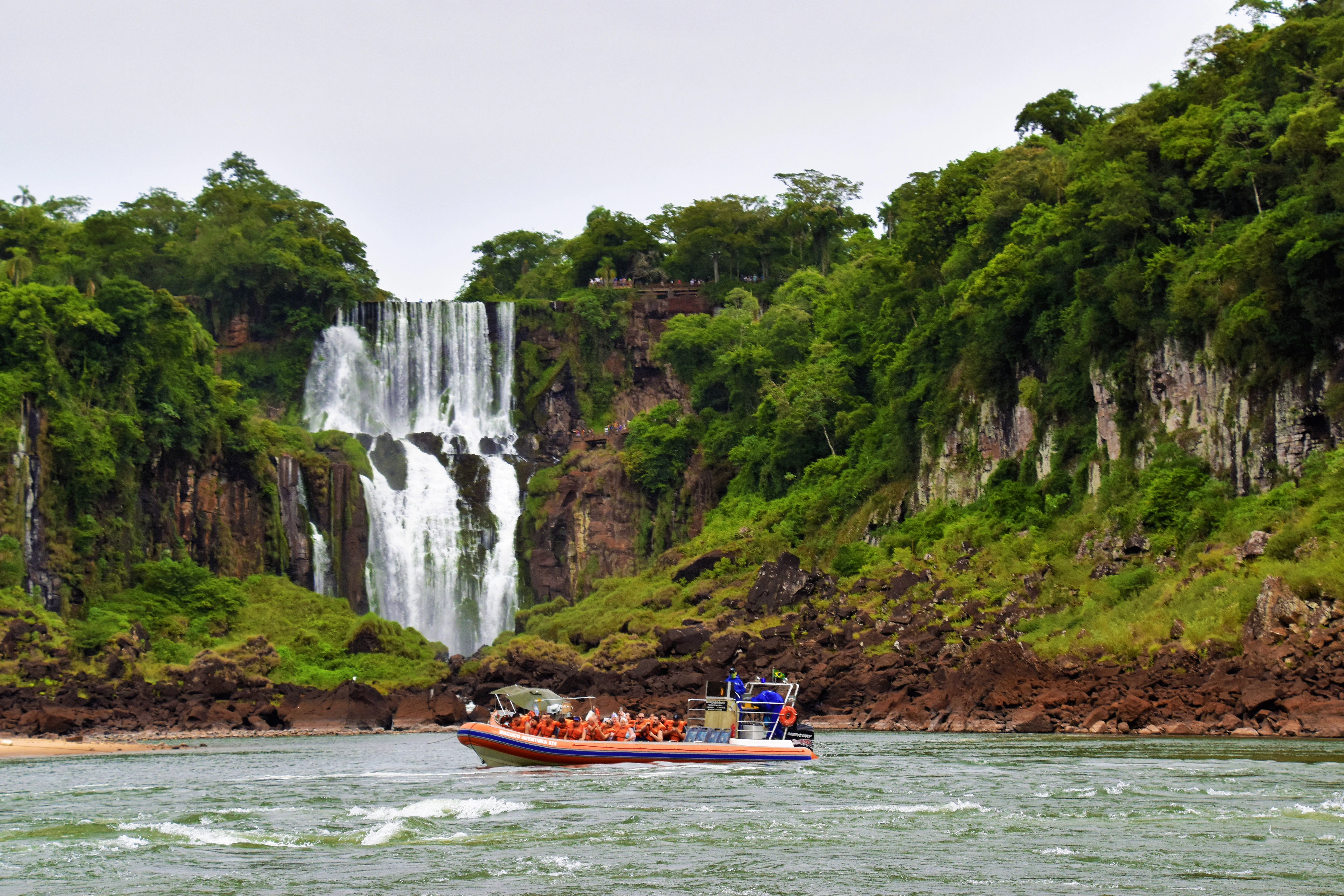 a boat in the water near a waterfall