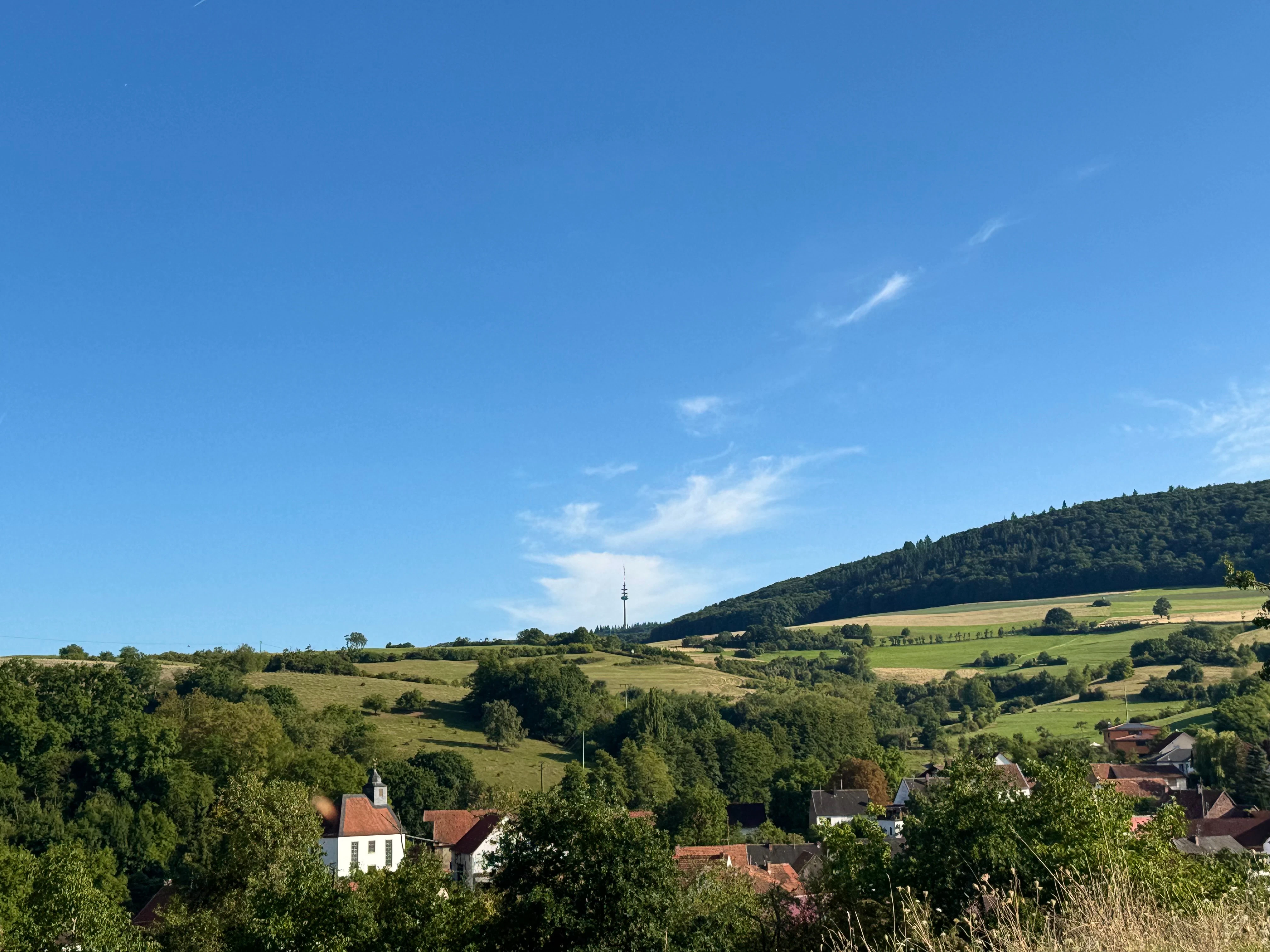 Village nestled in rolling green hills under blue sky