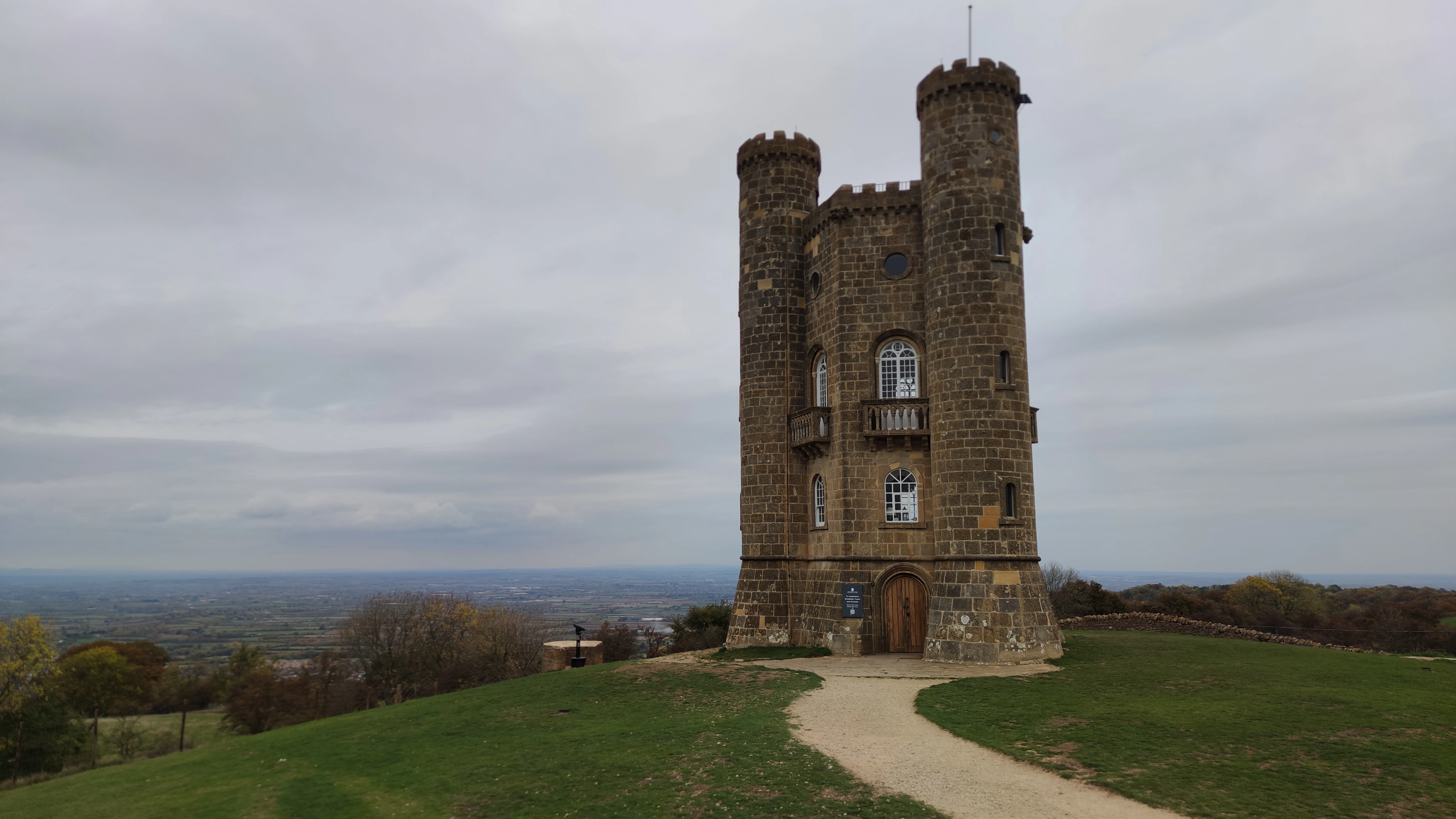 Stone tower on a grassy hill under cloudy sky