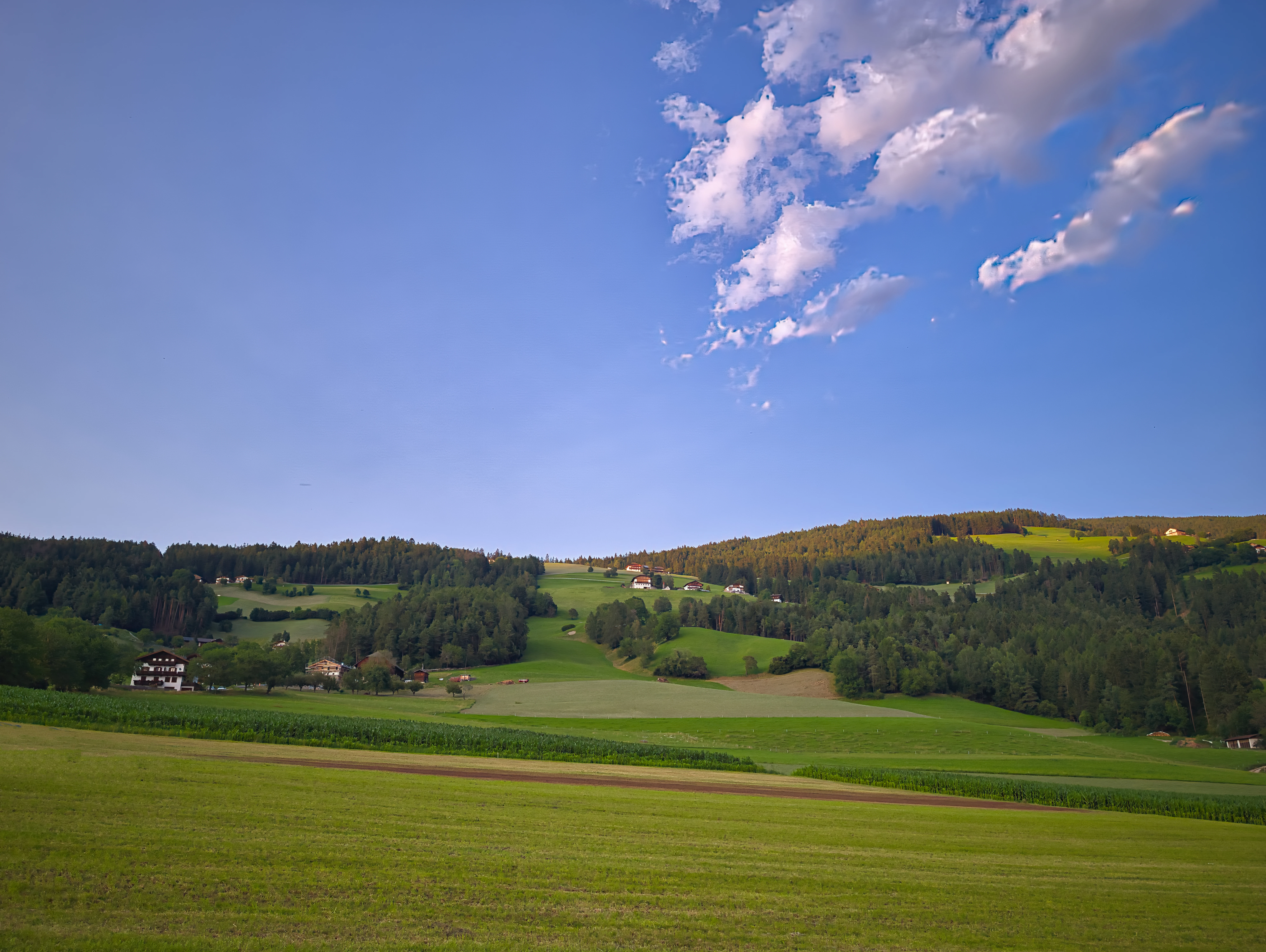 Green rolling hills under a blue sky with clouds