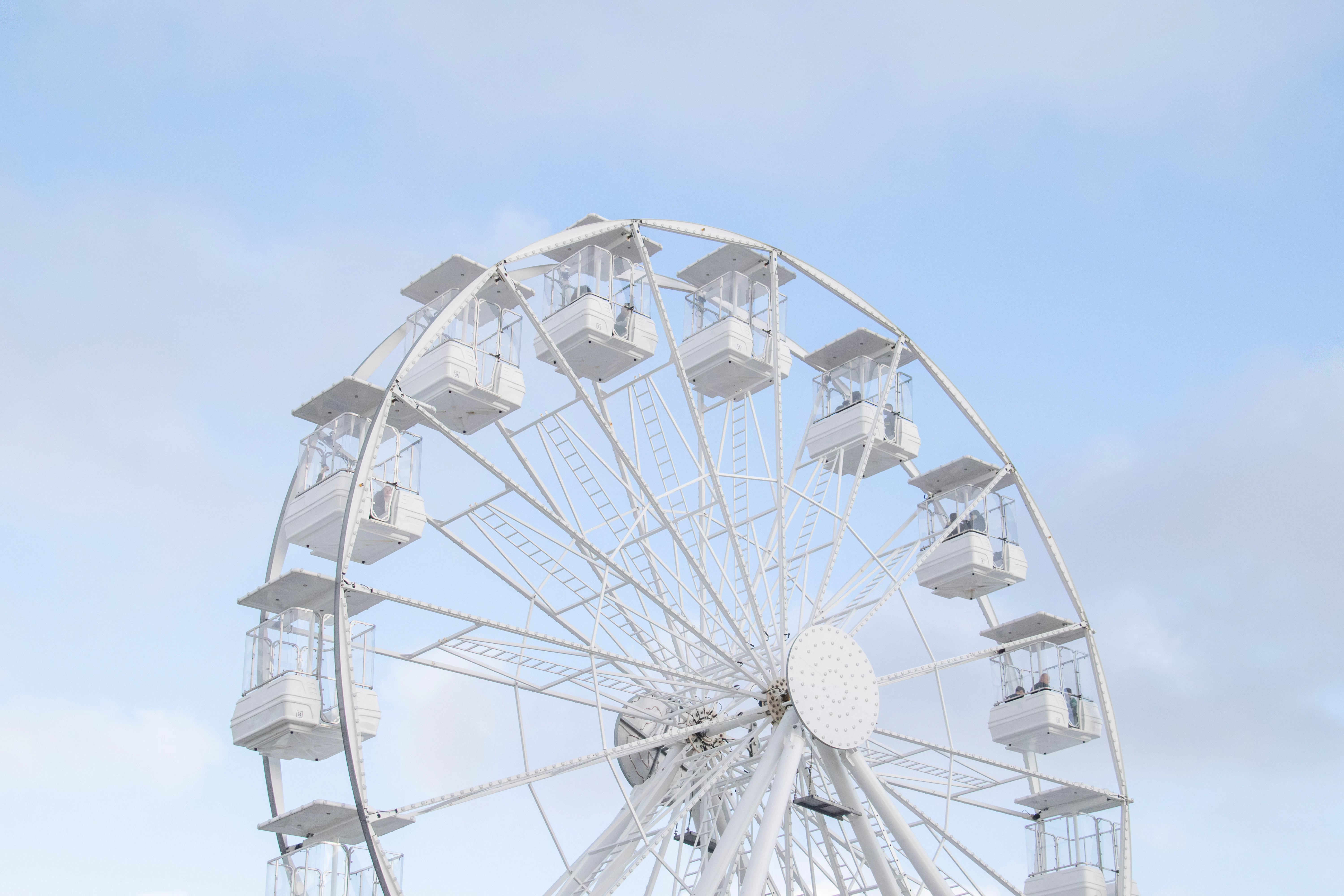A white ferris wheel against a cloudy sky.