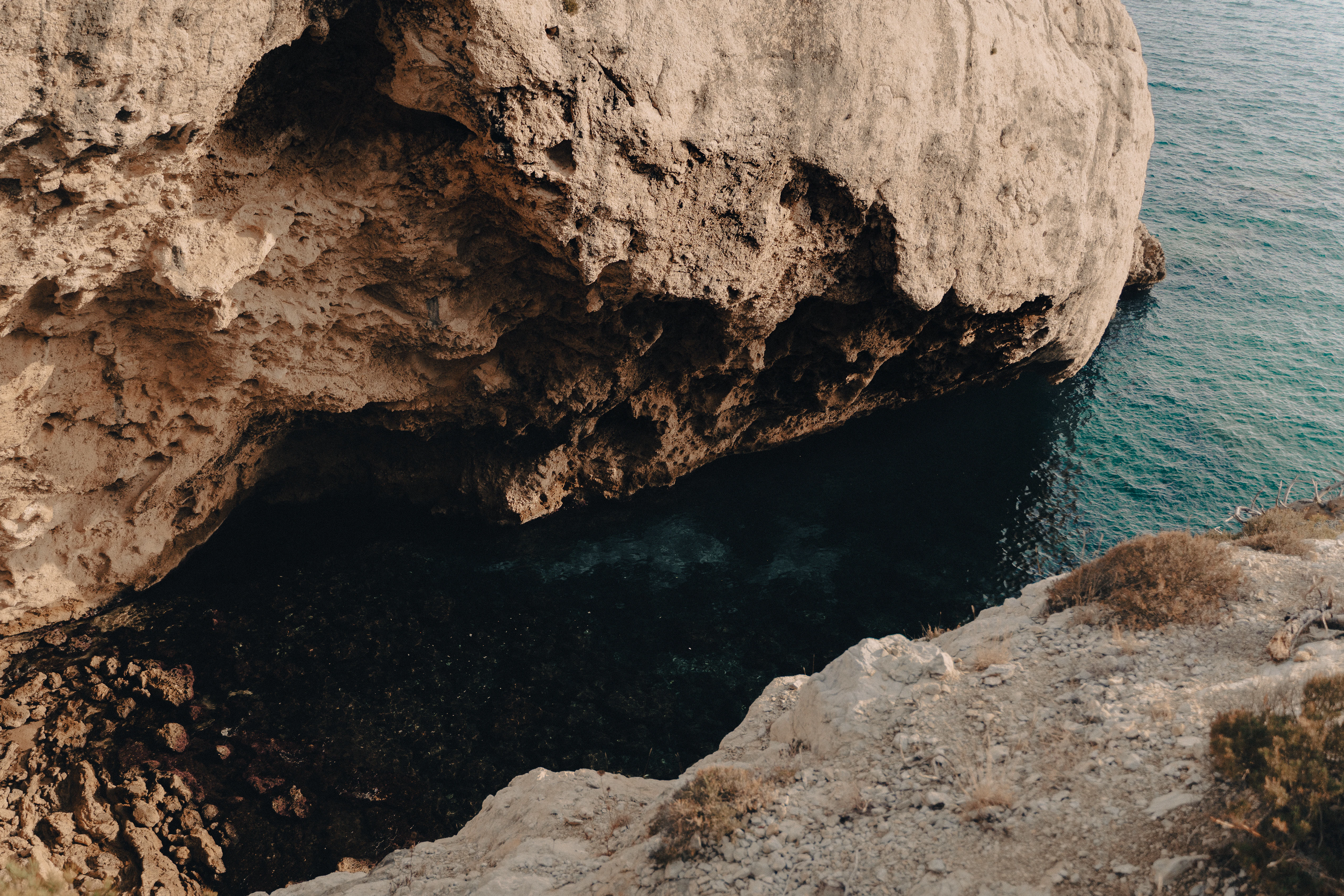 a rocky cliff with a body of water below