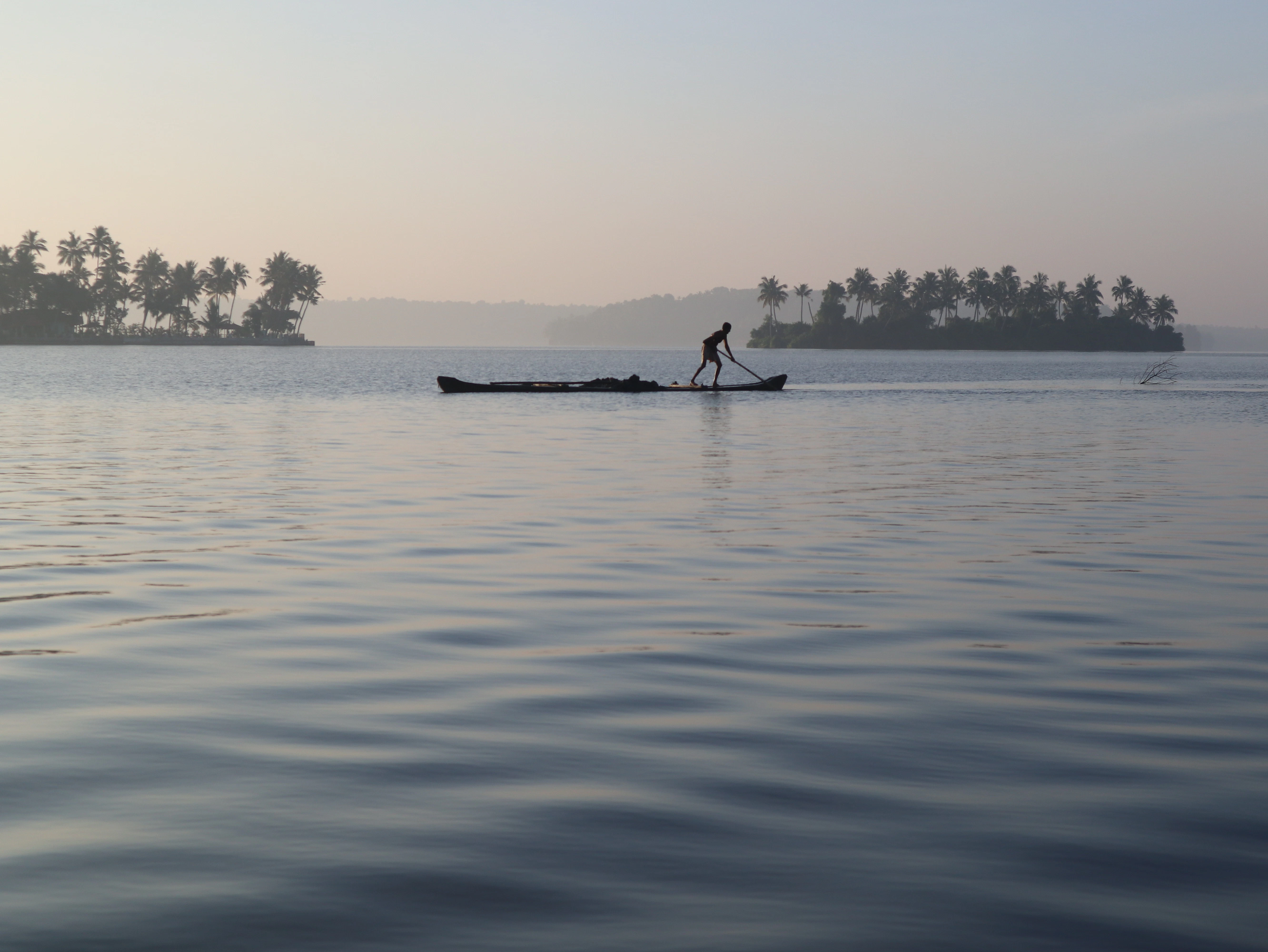 silhouette of 2 people riding on boat on sea during daytime