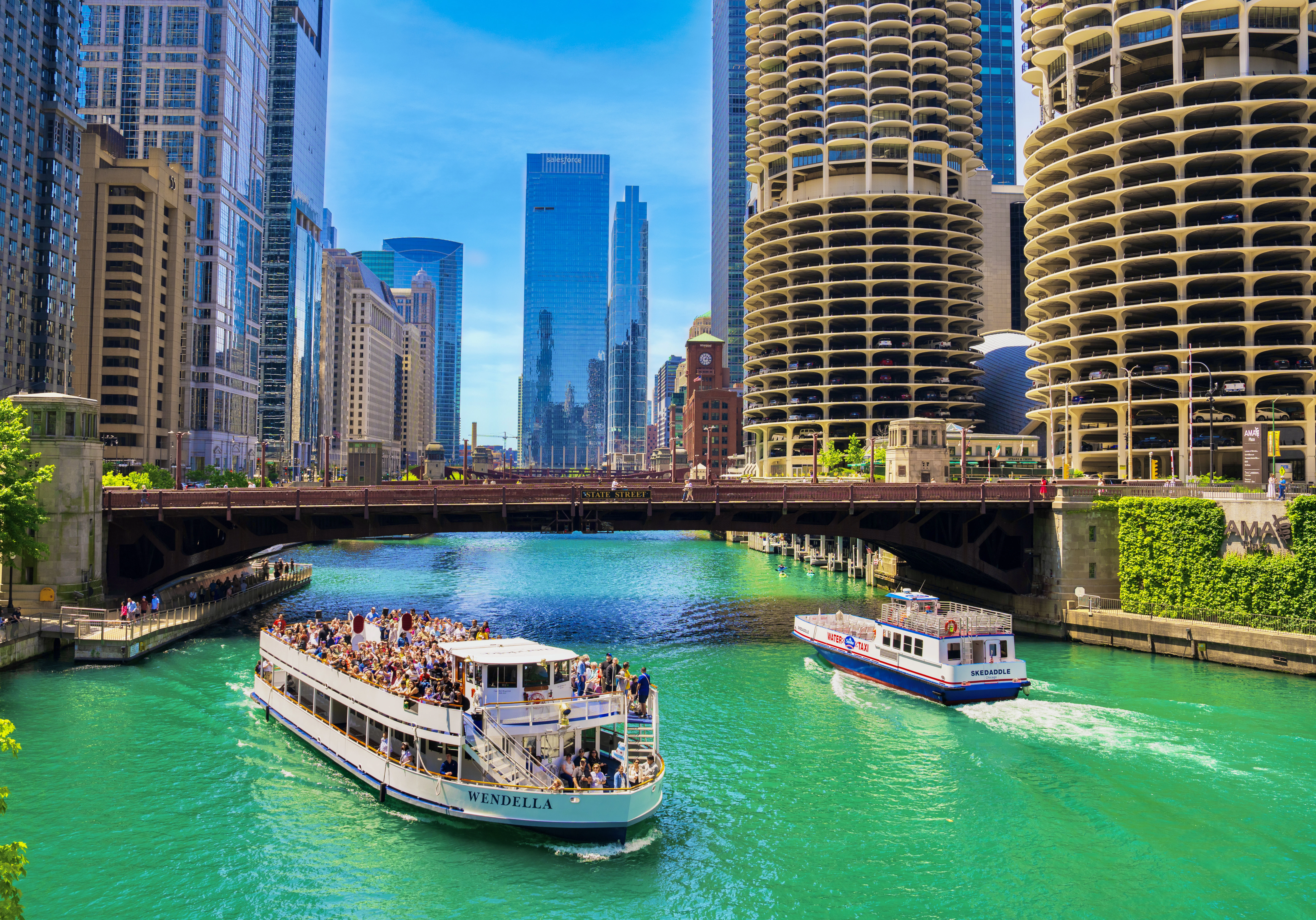 A river filled with lots of green water next to tall buildings