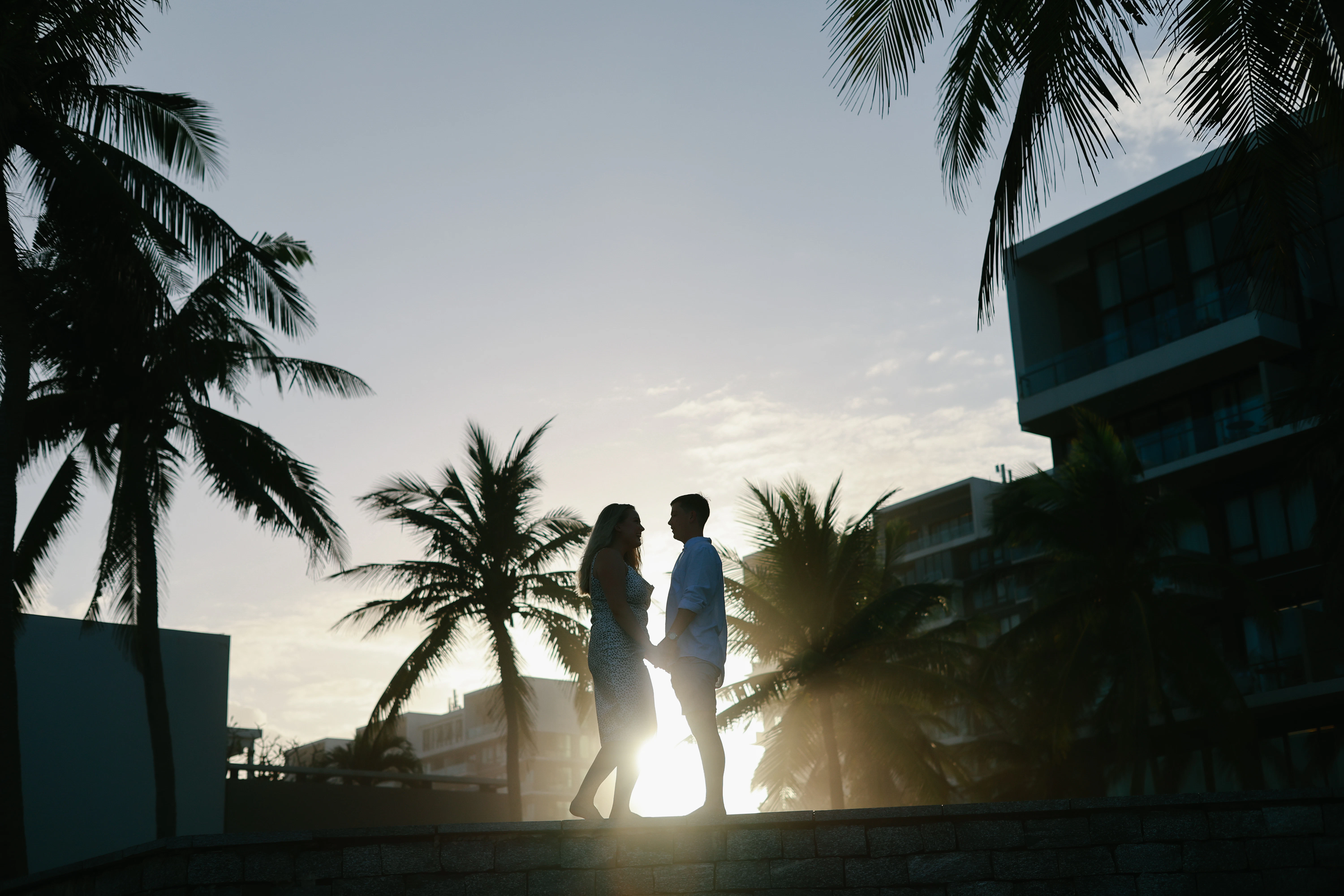 Couple holding hands at sunset with palm trees