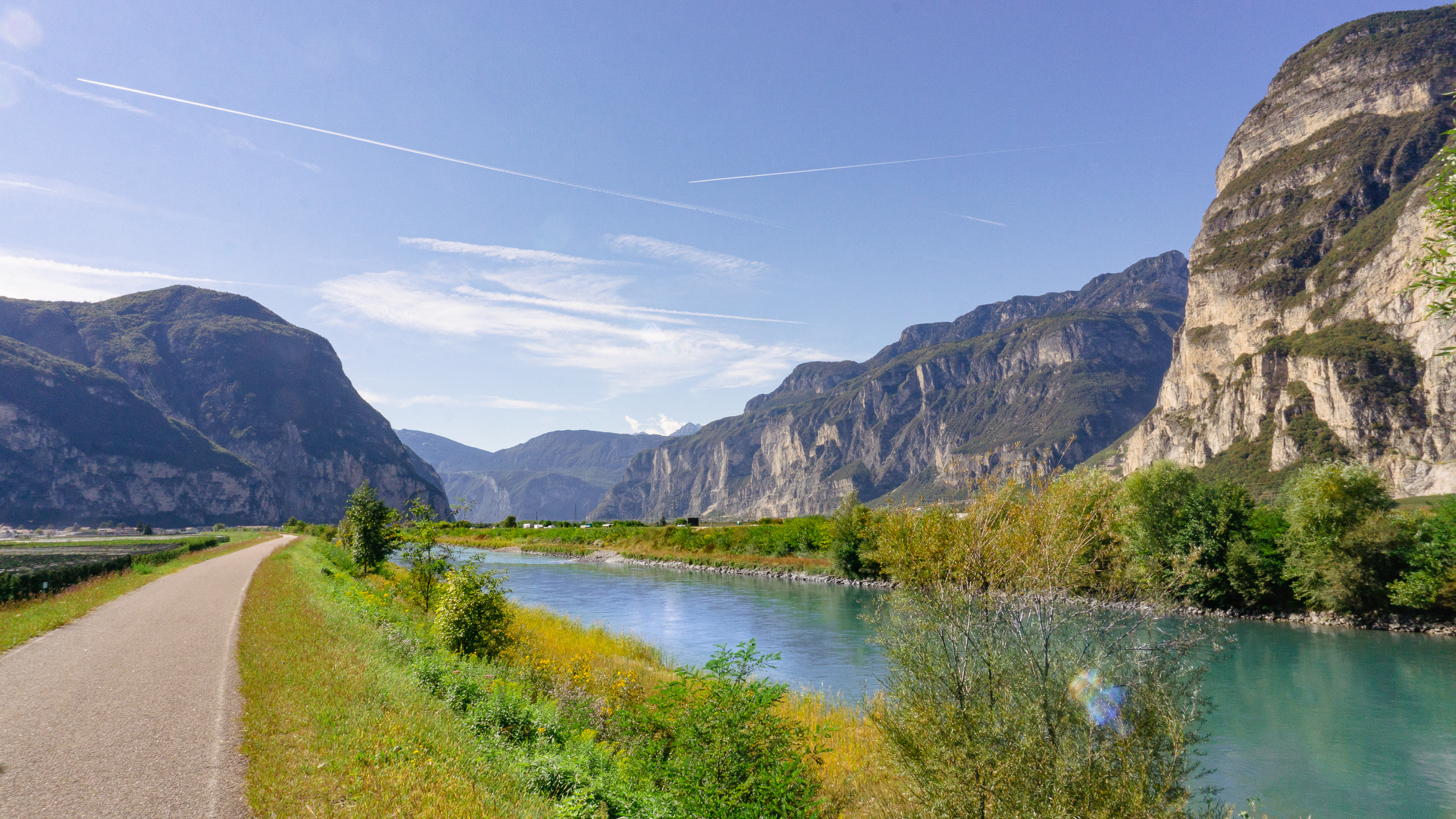 a road next to a body of water with mountains in the background
